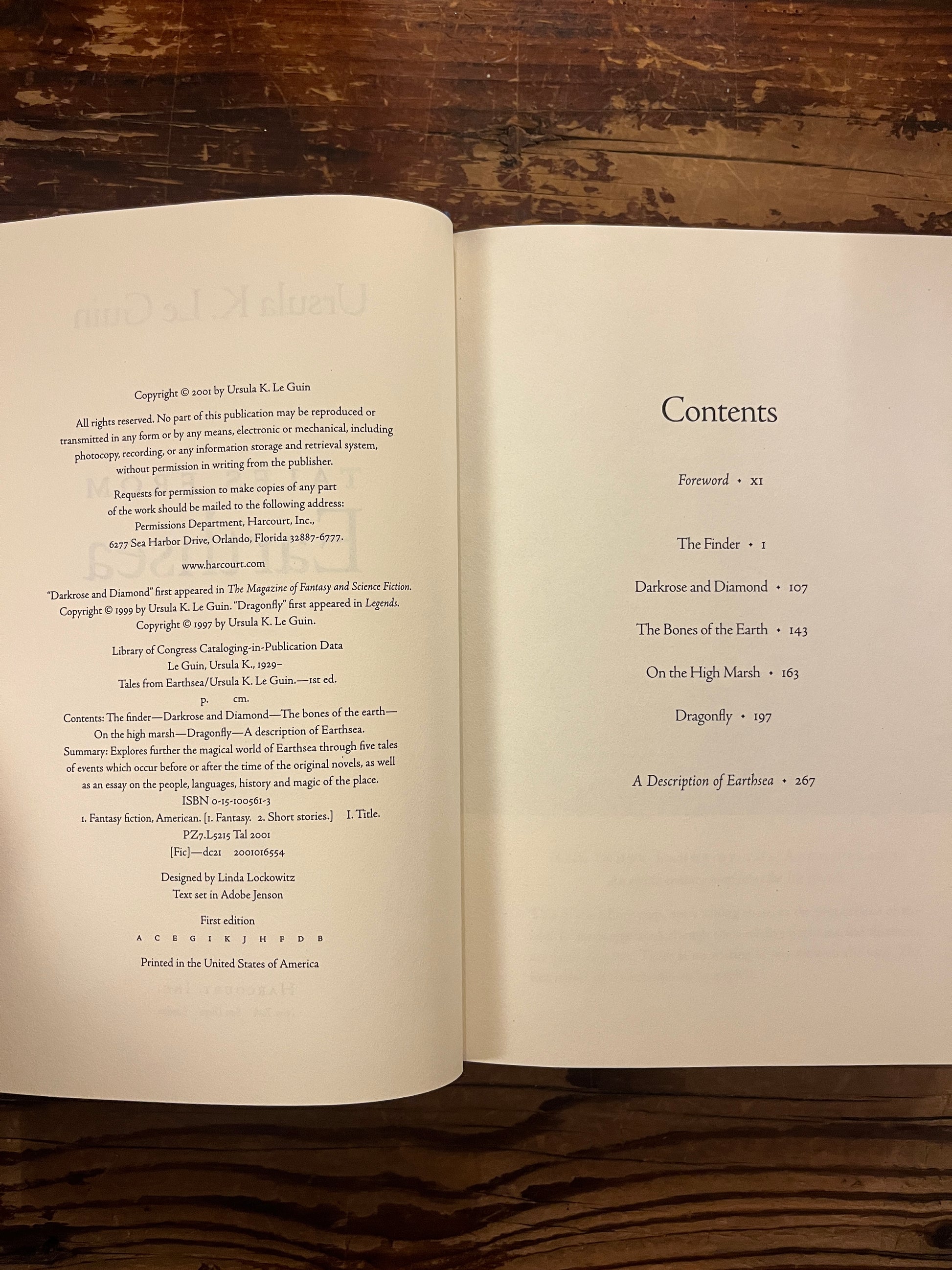 Open book showing the contents of a book titled 'Tales from Earthsea' by Ursula K. Le Guin on a wooden surface