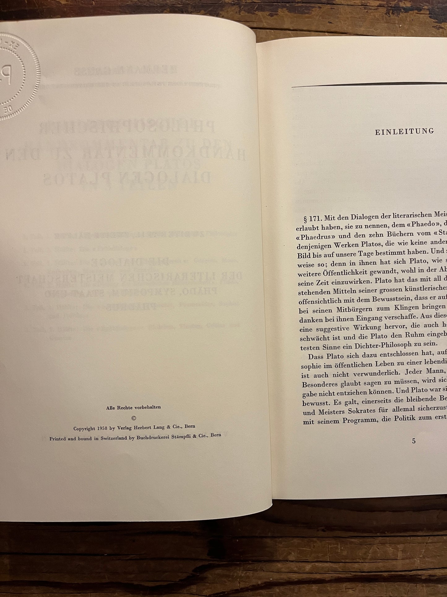 Open book titled 'Philosophischer Handkommentar zu den Dialogen Platos' by H. Gauss on a wooden surface 