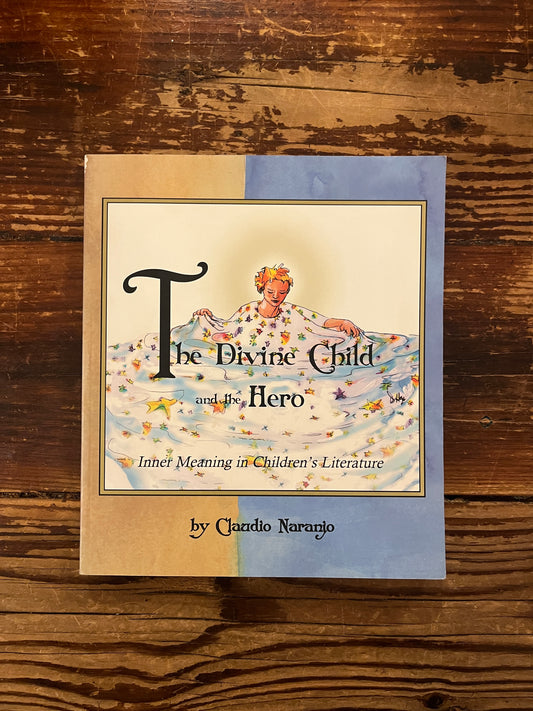 Book titled 'The Divine Child and the Hero' by Claudio Naranjo on a wooden surface