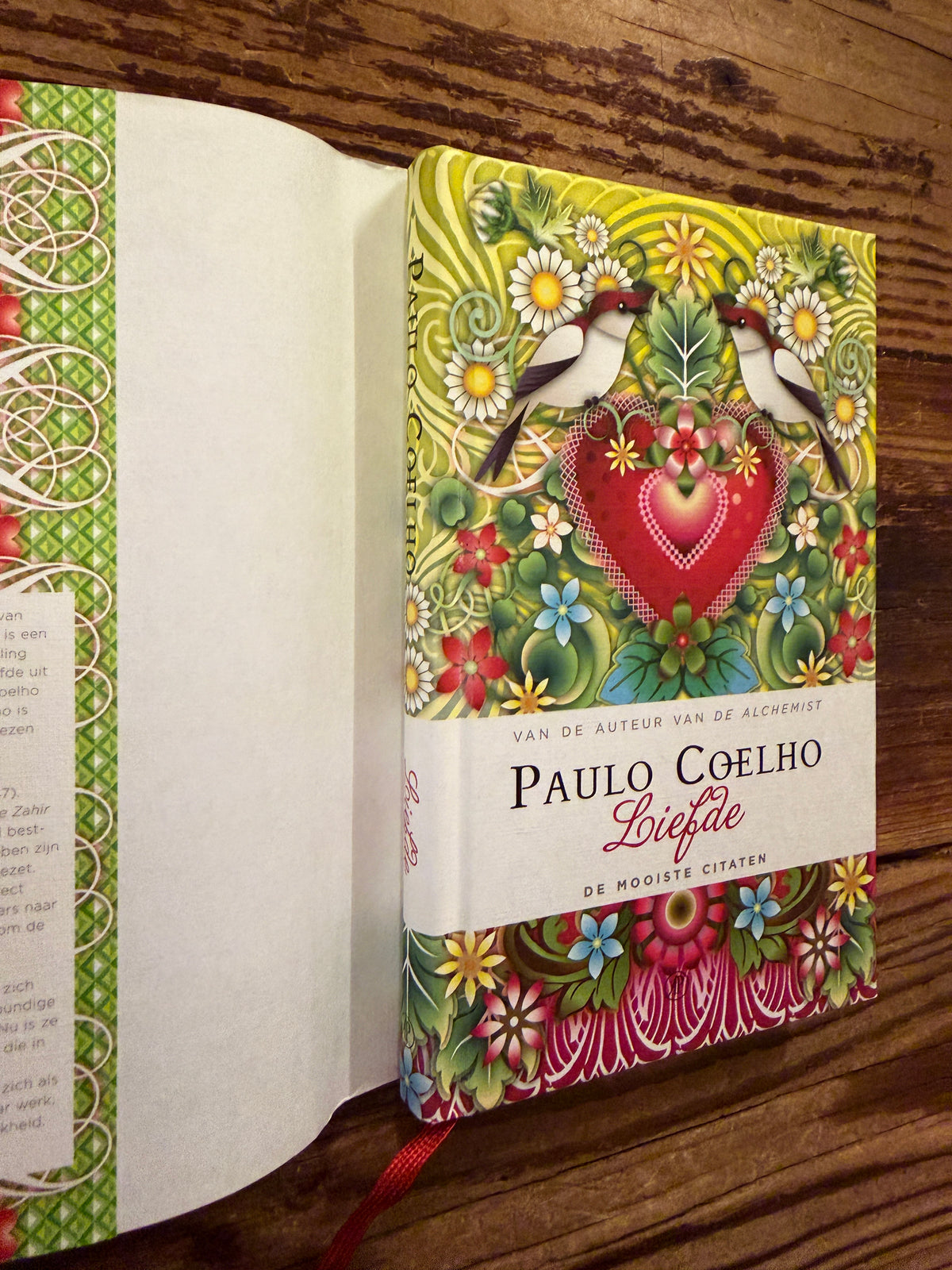 Voorkant  en rug zonder stof omslag van boek met de titel 'liefde' door Paulo Coelho op een houten achtergrond