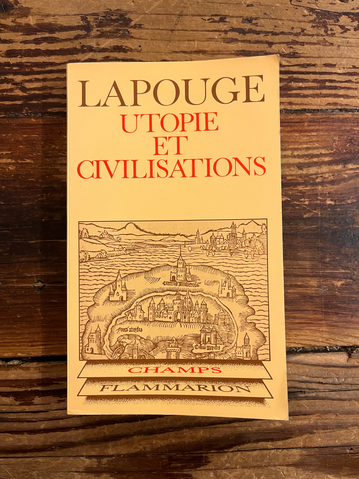 Couverture du livre de poche dont le titre est 'Utopie et civilisations' par Lapouge, exposé sur une surface en bois