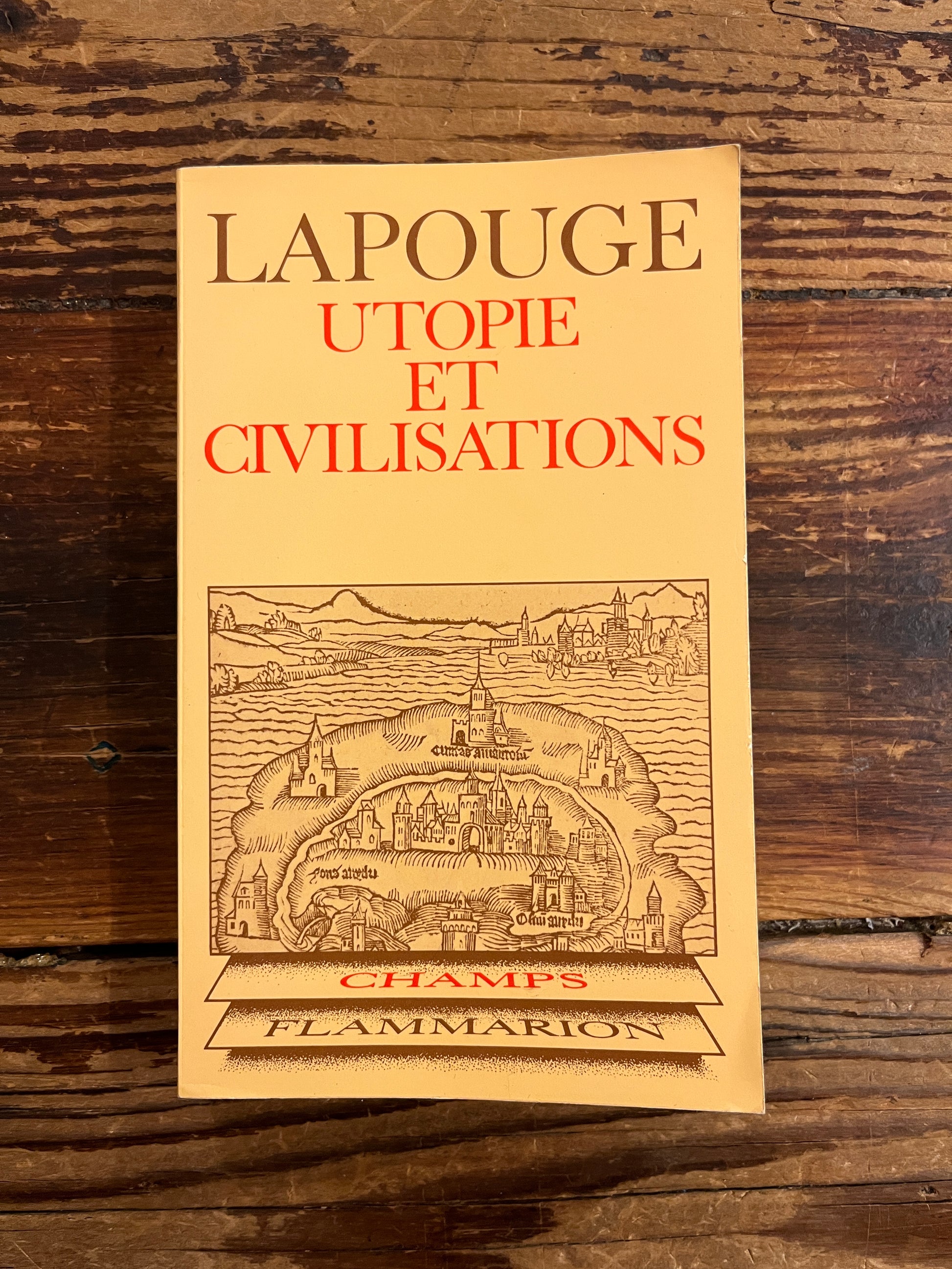 Couverture du livre de poche dont le titre est 'Utopie et civilisations' par Lapouge, exposé sur une surface en bois