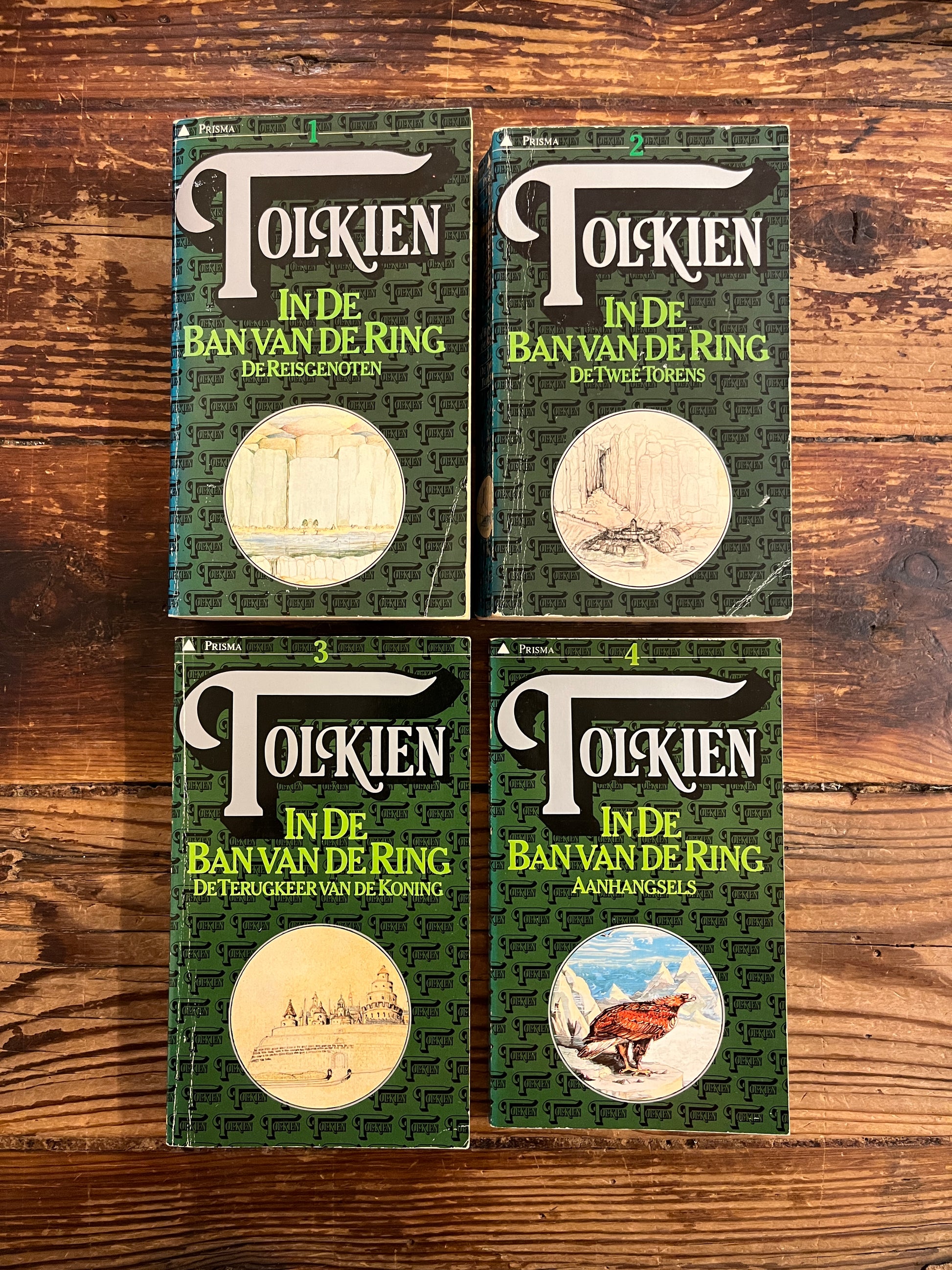 Vier boeken van Tolkien 'in de ban van de ring' deel een tot en met deel drie plus de aanhangsels op een houten achtergrond 