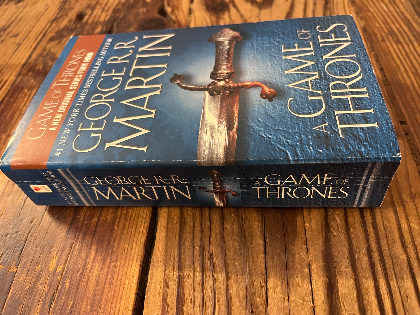 A Game of thrones, book one of the song of ice and fire series, spine and front cover visible on a wooden back ground 
