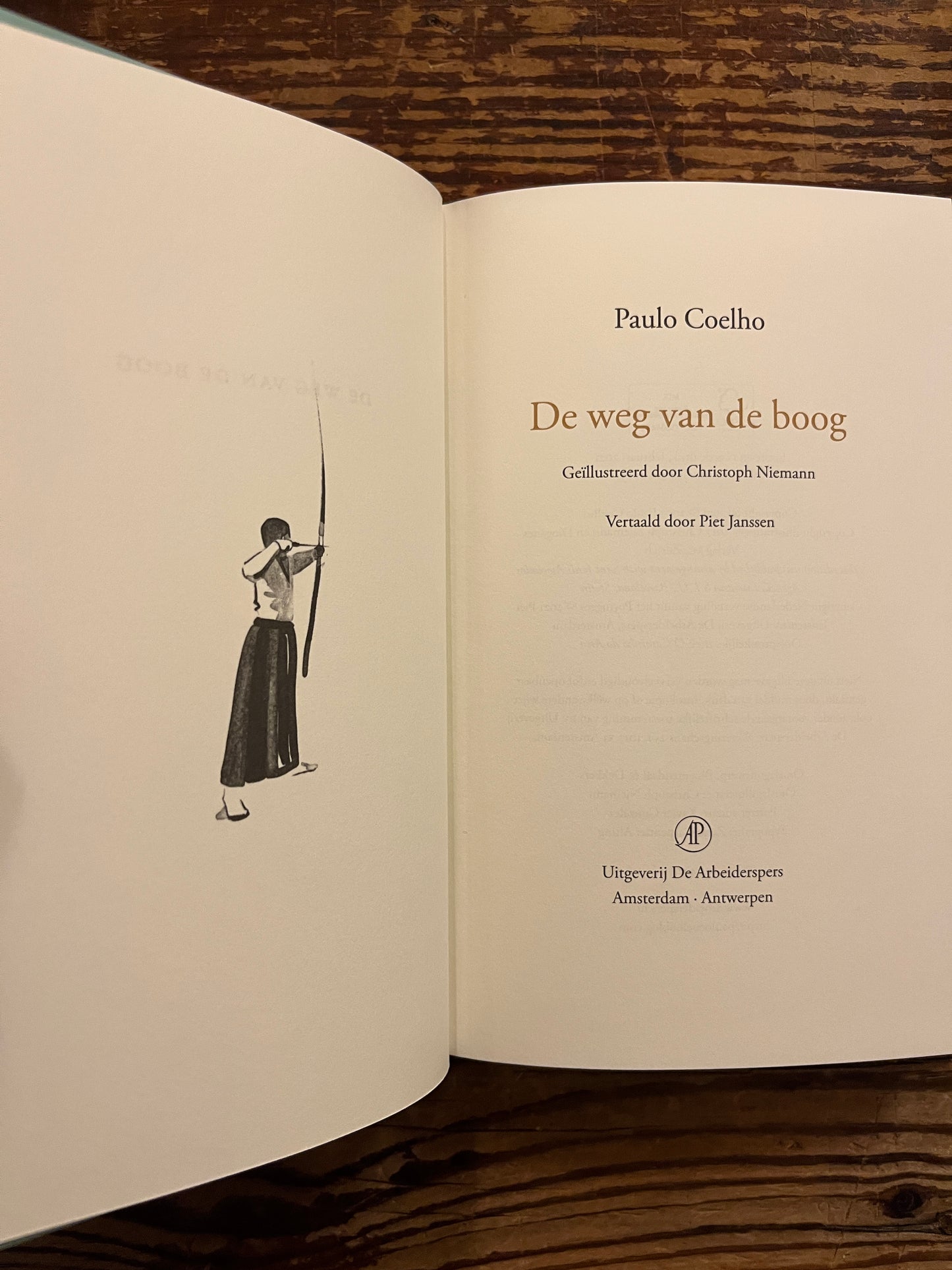 Open boek 'de weg van de boog' door Paulo Coelho op een houten achtergrond 