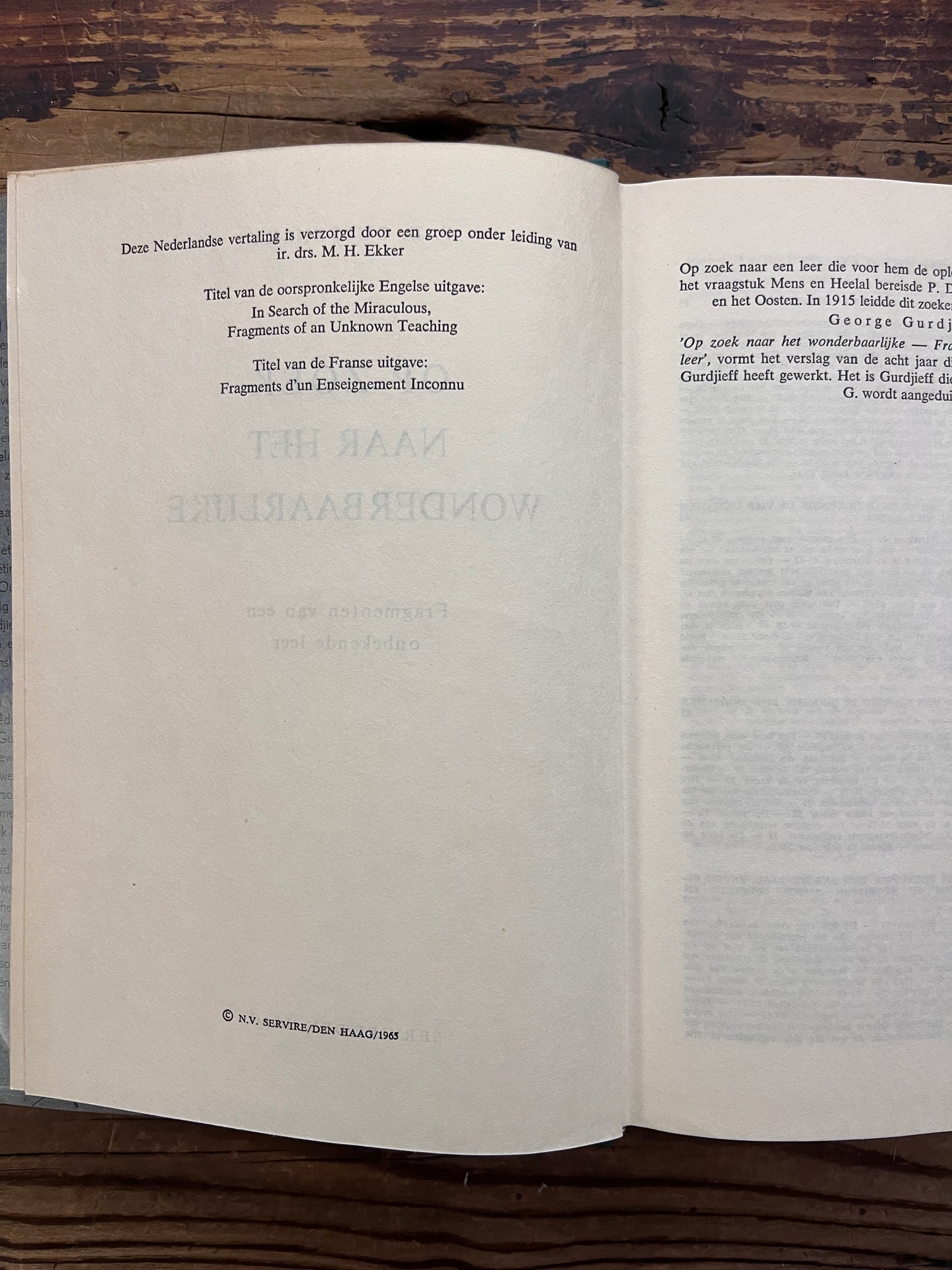 Open boek met de titel 'op zoek naar het wonderbaarlijke, fragmenten van een onbekende leer' door P. D.  Ouspensky op een houten achter grond 