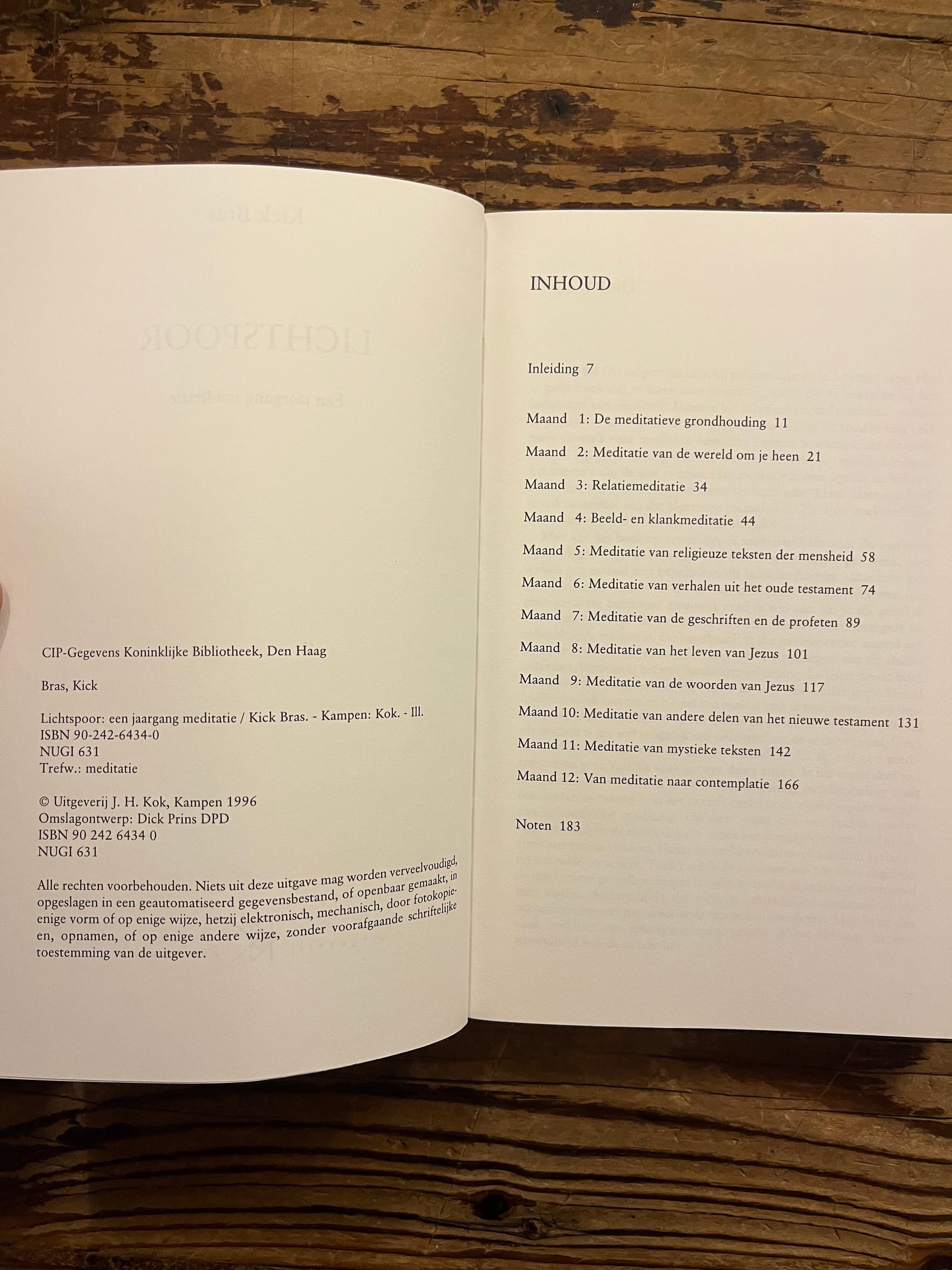 Open boek 'lichtspoor' door Kick Bras op een houten achtergrond 