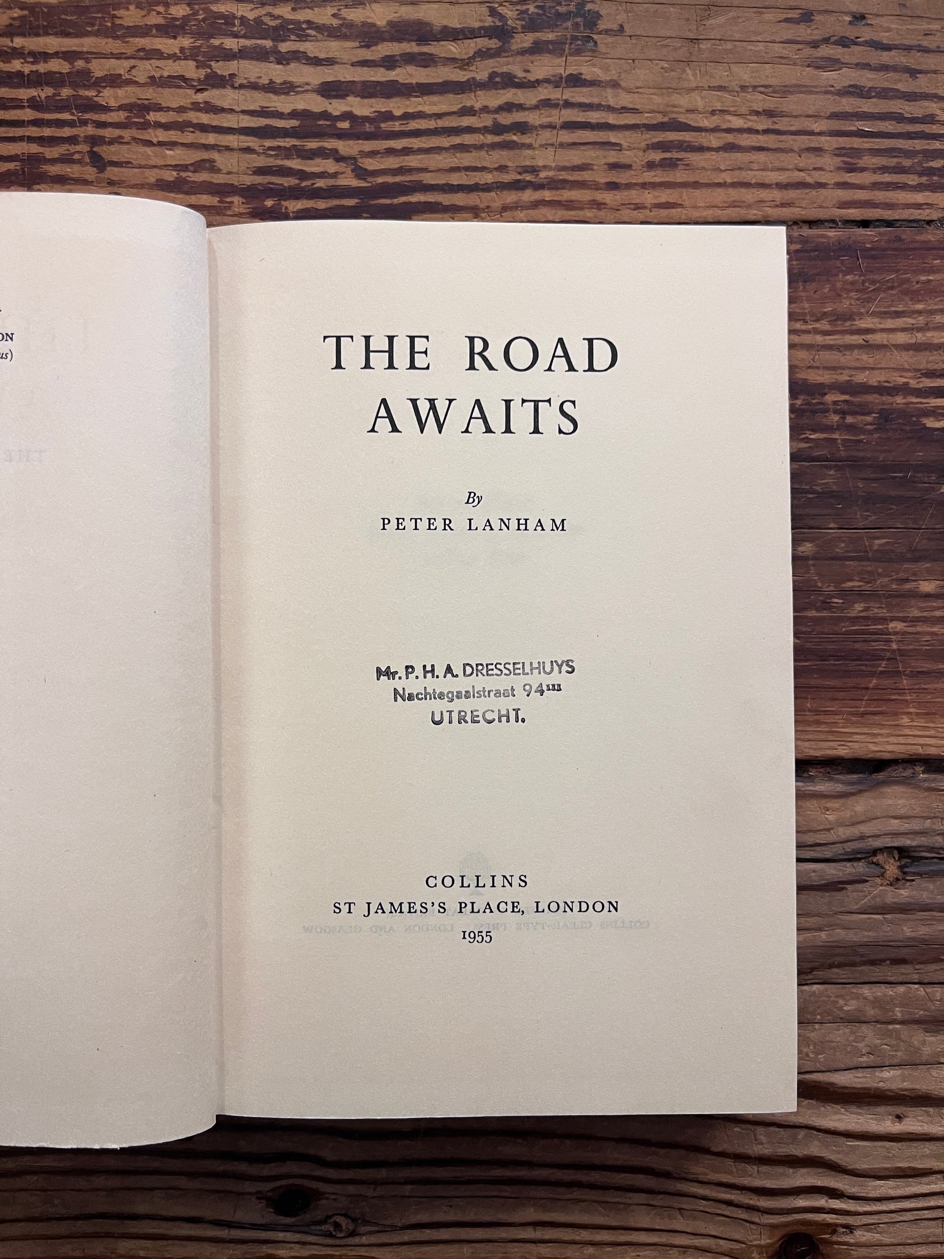 Book titled 'The Road Waits' by Peter Lanham on a wooden surface