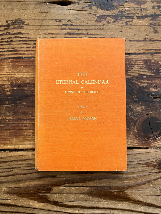 Front cover of book with the tile 'the eternal calendar' by Minnie Theobald on a wooden surface