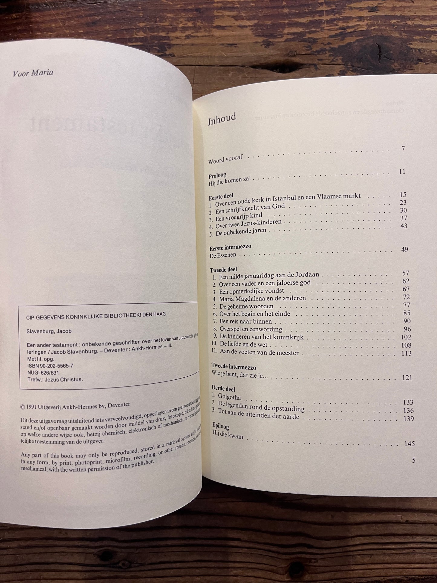 Open boek met de titel 'Een ander testament' door J. Slavenburg op een houten achtergrond 