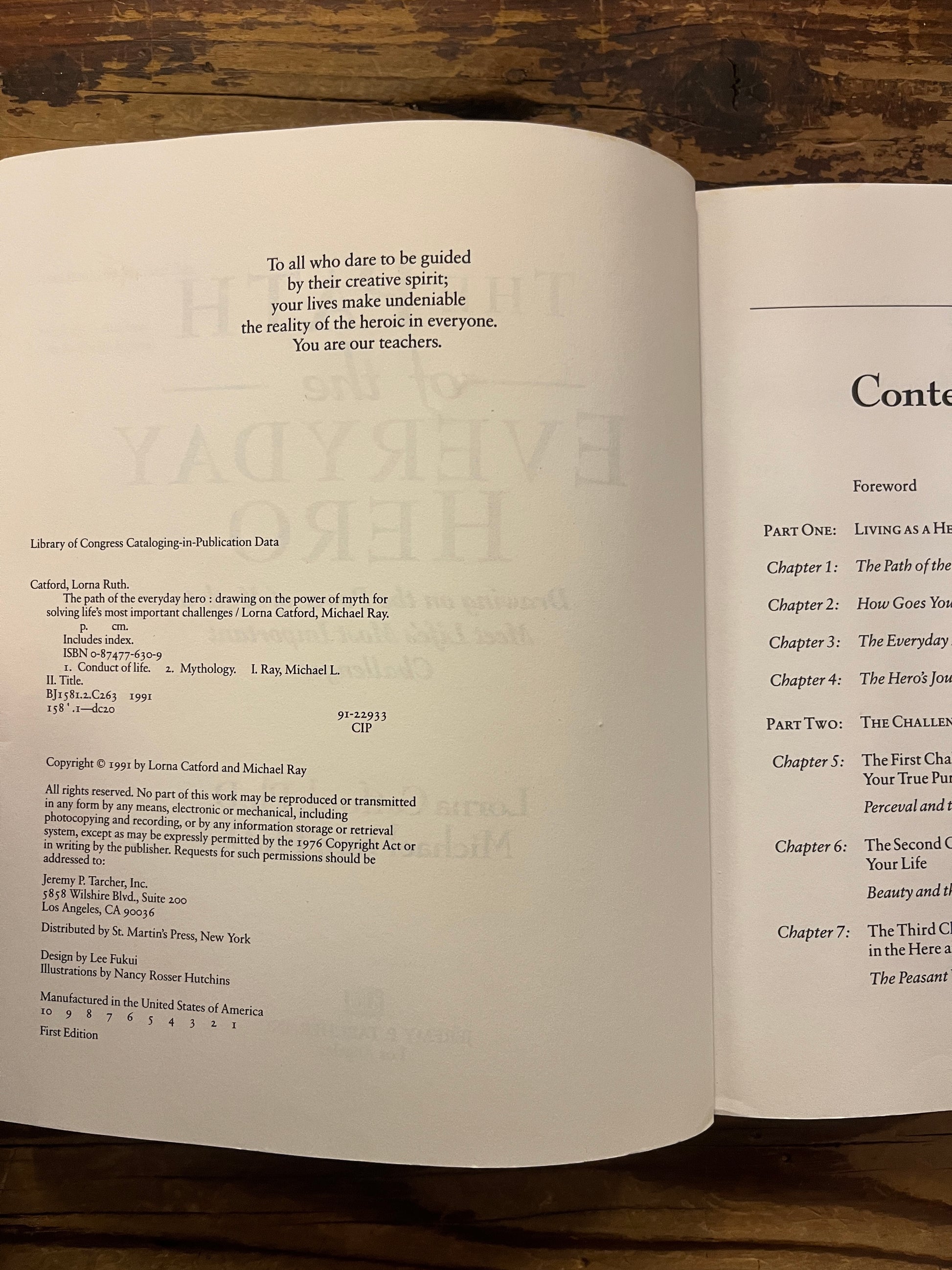 Open book titled 'The Path of the Everyday Hero' on a wooden surface