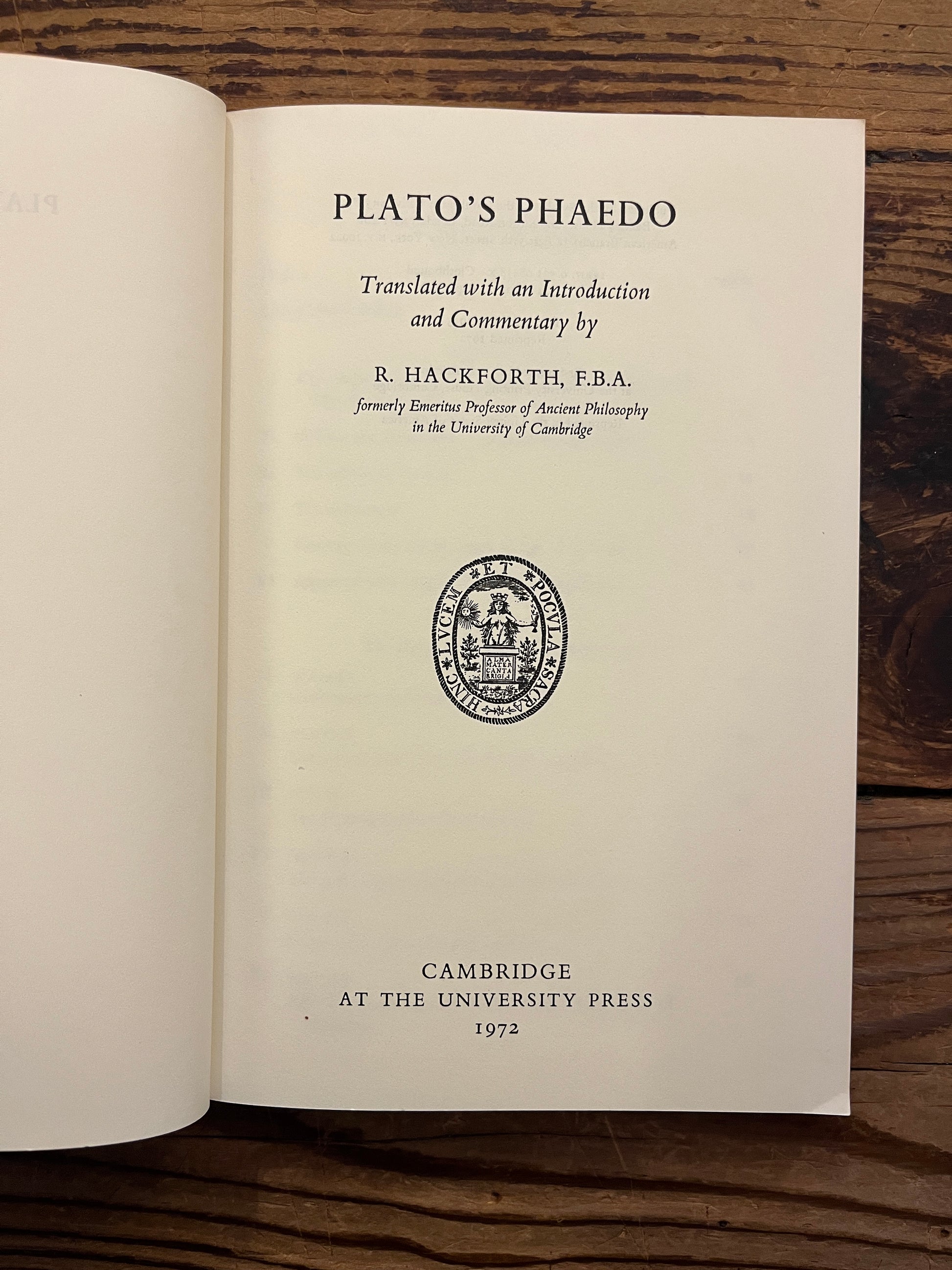 Open book titled 'Plato's Phaedo' translated with an introduction and commentary by R. Hackforth on a wooden surface