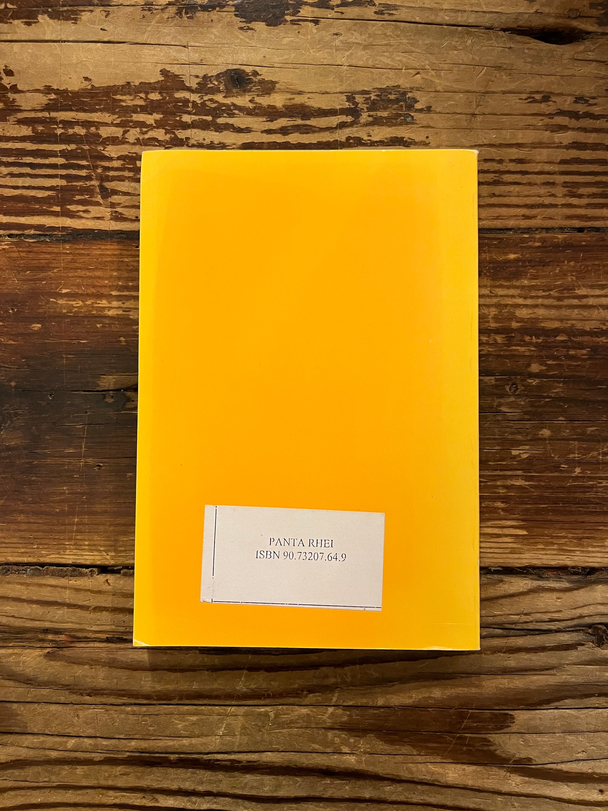 Achterkant van boek 'De Wereld van het Denken'  door Inayat Khan on a wooden surface