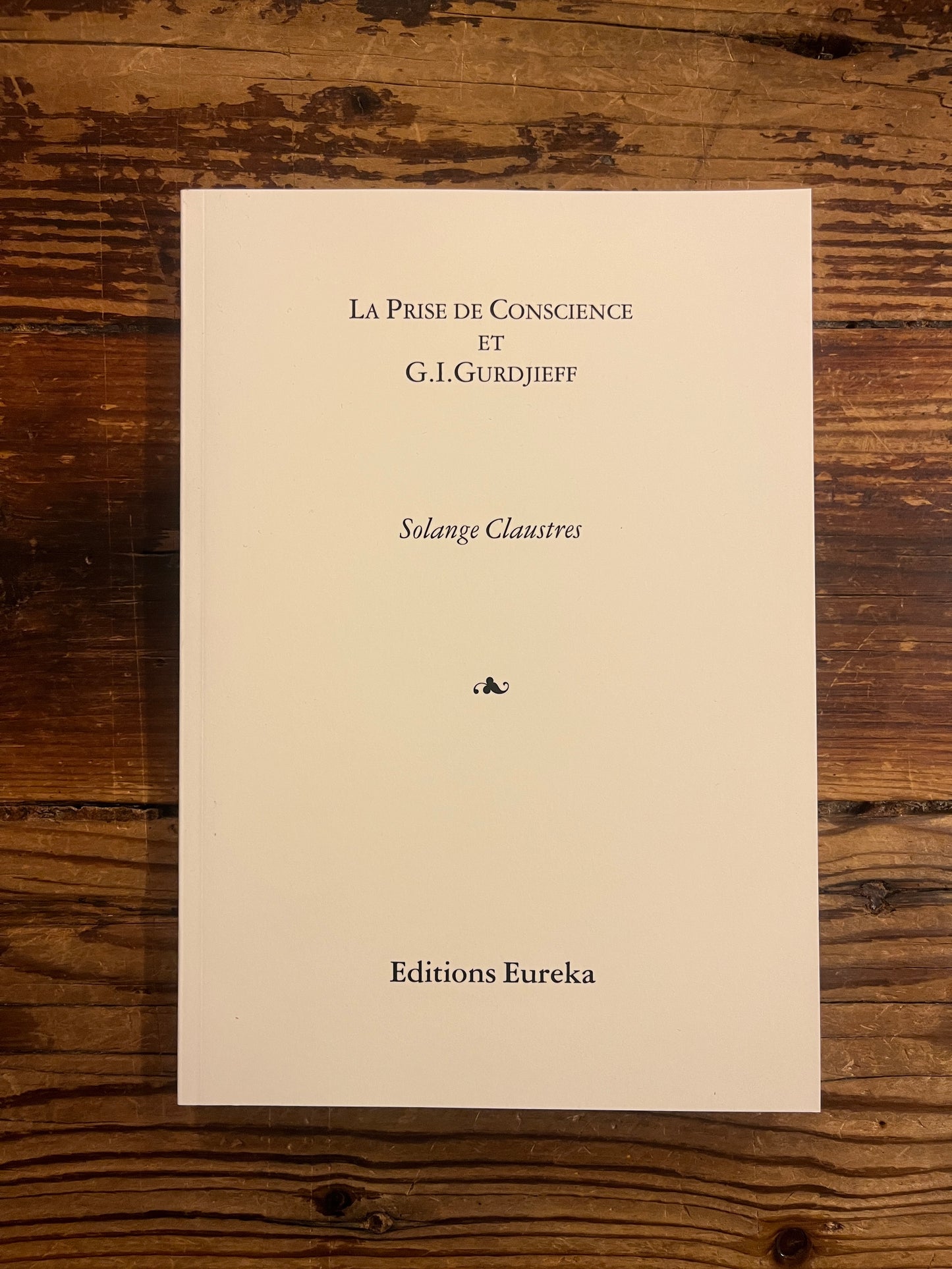 Livre 'la prise de conscience et G.I. Gurdjieff' par Solange Claustres sur un fond en bois