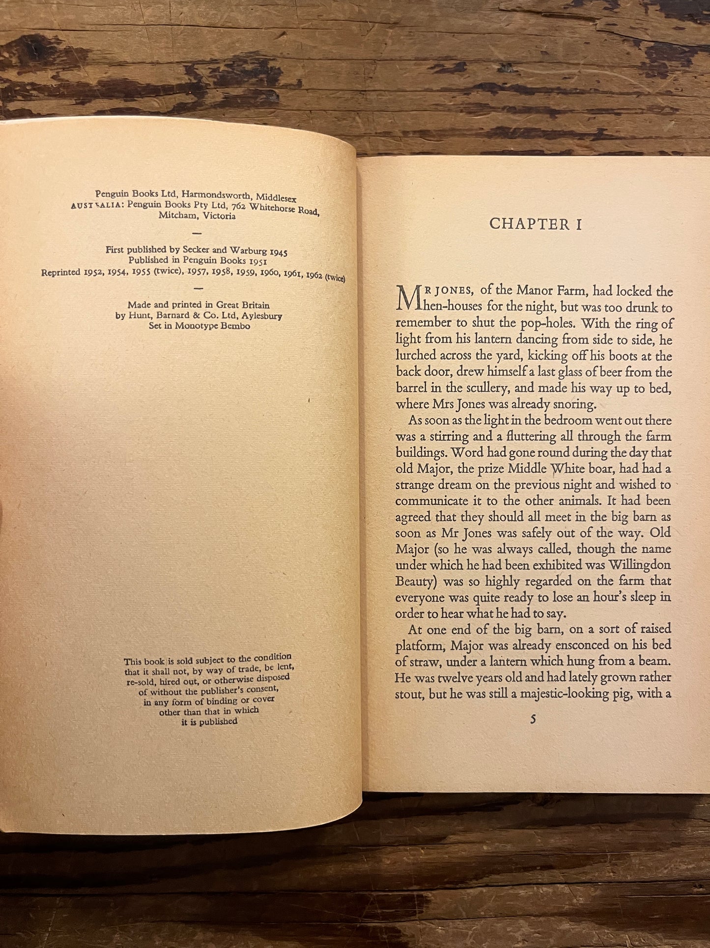 Open book titled 'Animal farm' by George Orwell on a wooden surface