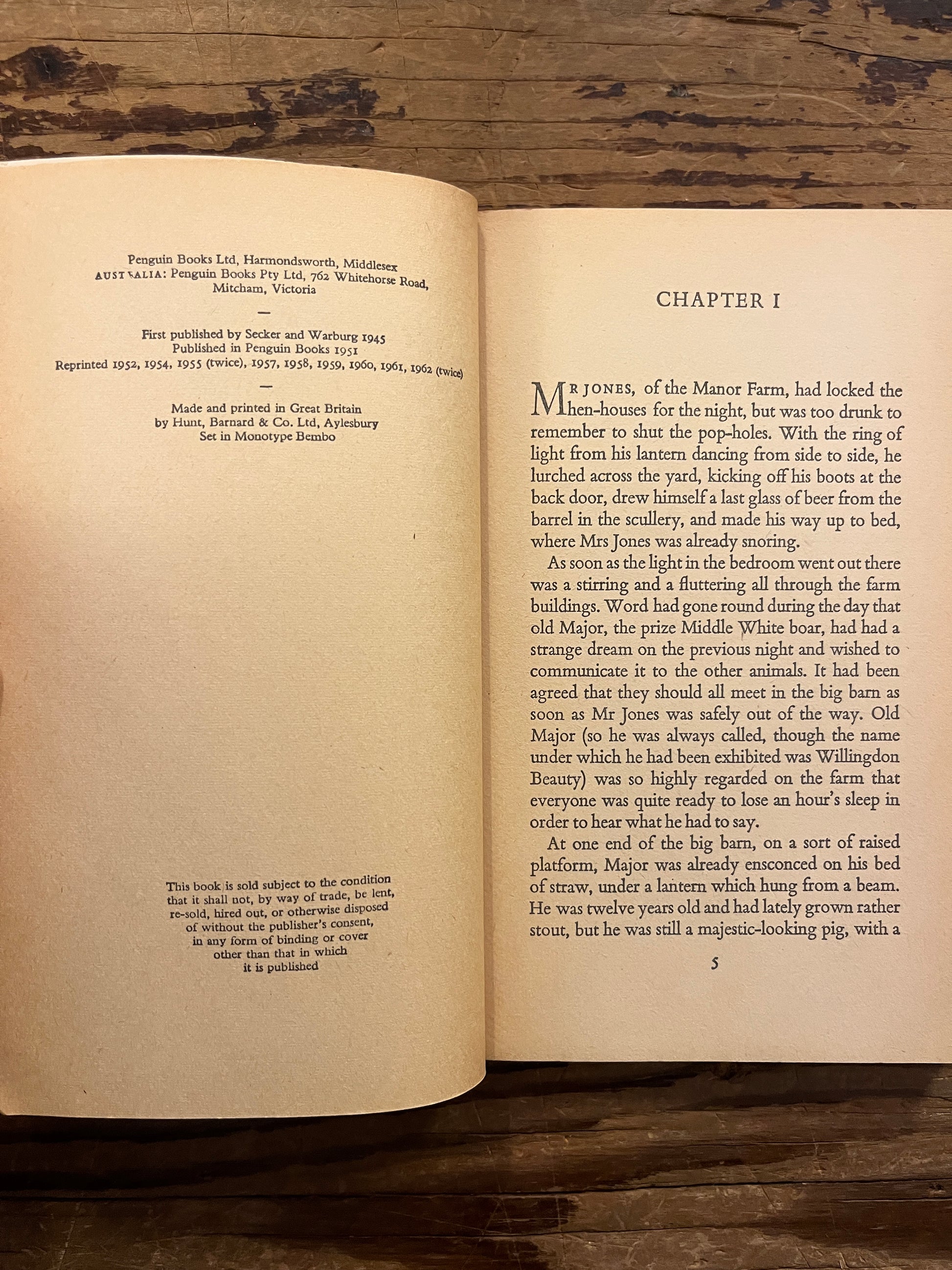 Open book titled 'Animal farm' by George Orwell on a wooden surface