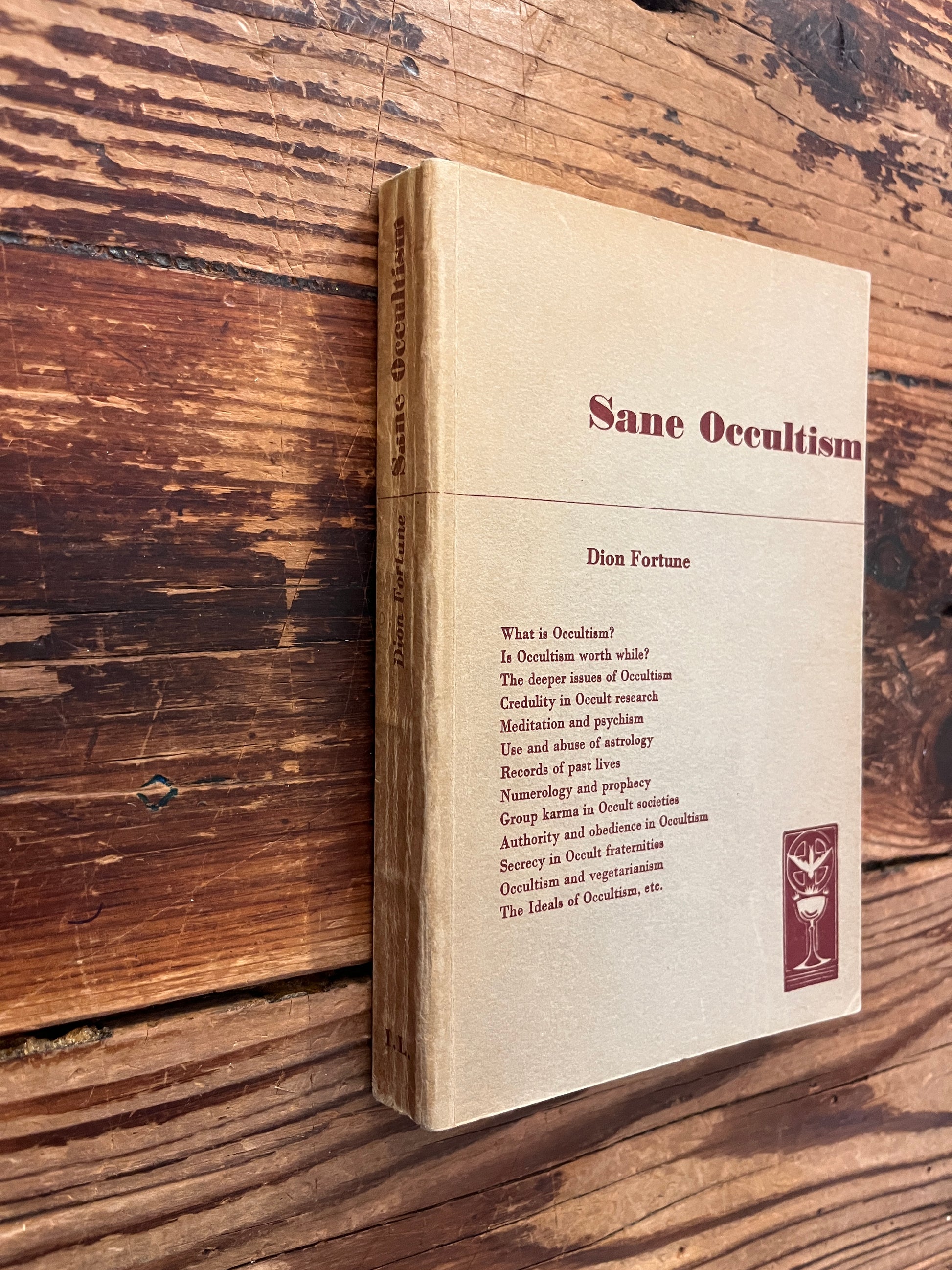 Spine and front cover of rare first cheap edition of book titled 'sane occultism' by Dion Fortune on a wooden surface 
