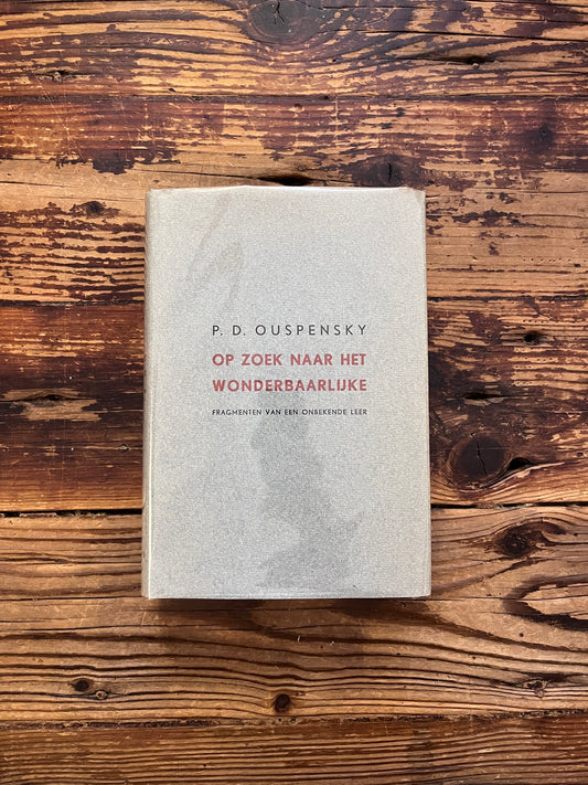 Voorkant van boek met de titel 'op zoek naar het wonderbaarlijke, fragmenten van een onbekende leer' door P. D.  Ouspensky op een houten achter grond 