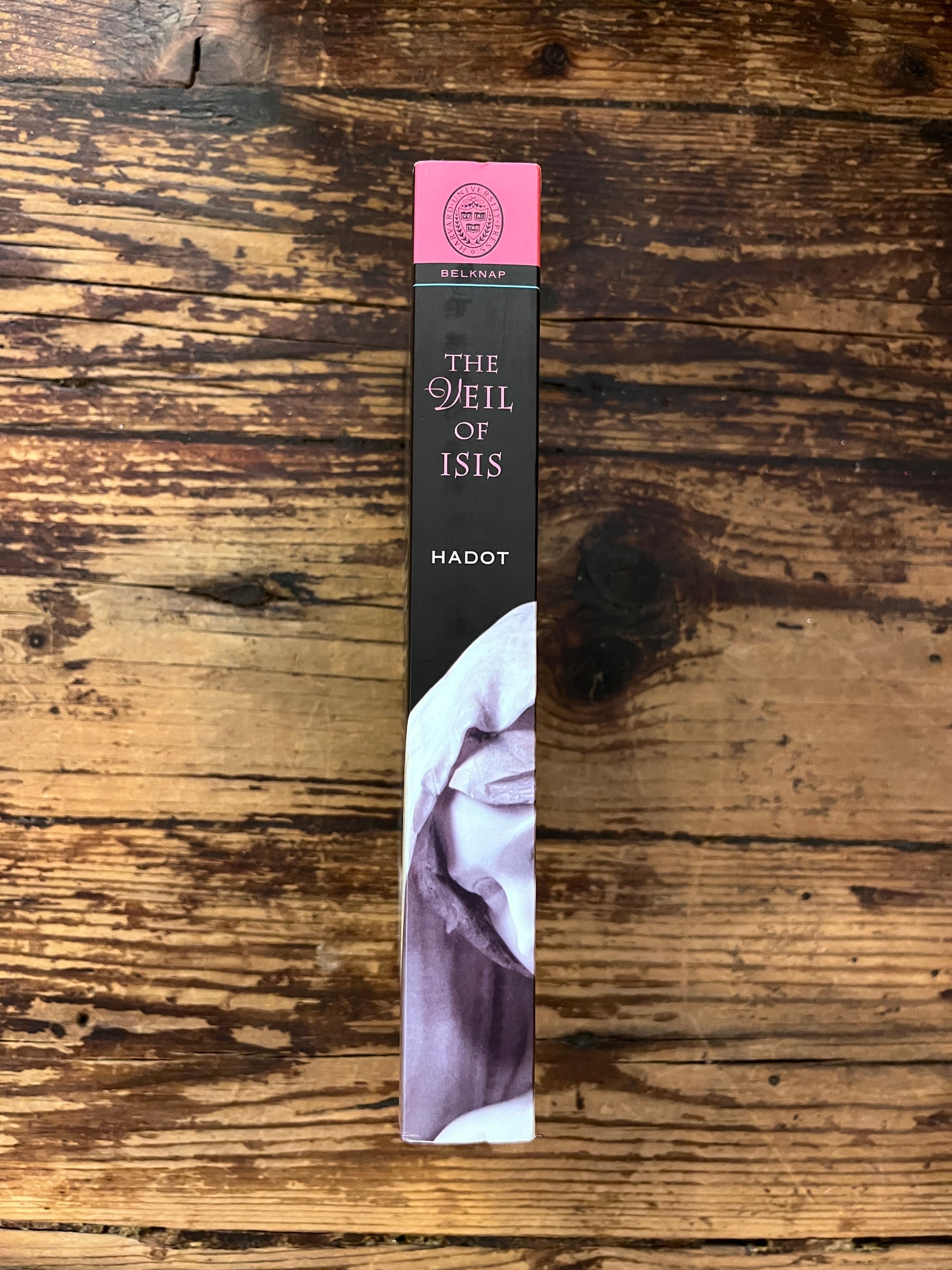 photo of the spine of the book "the veil of isis" on a wooden background
