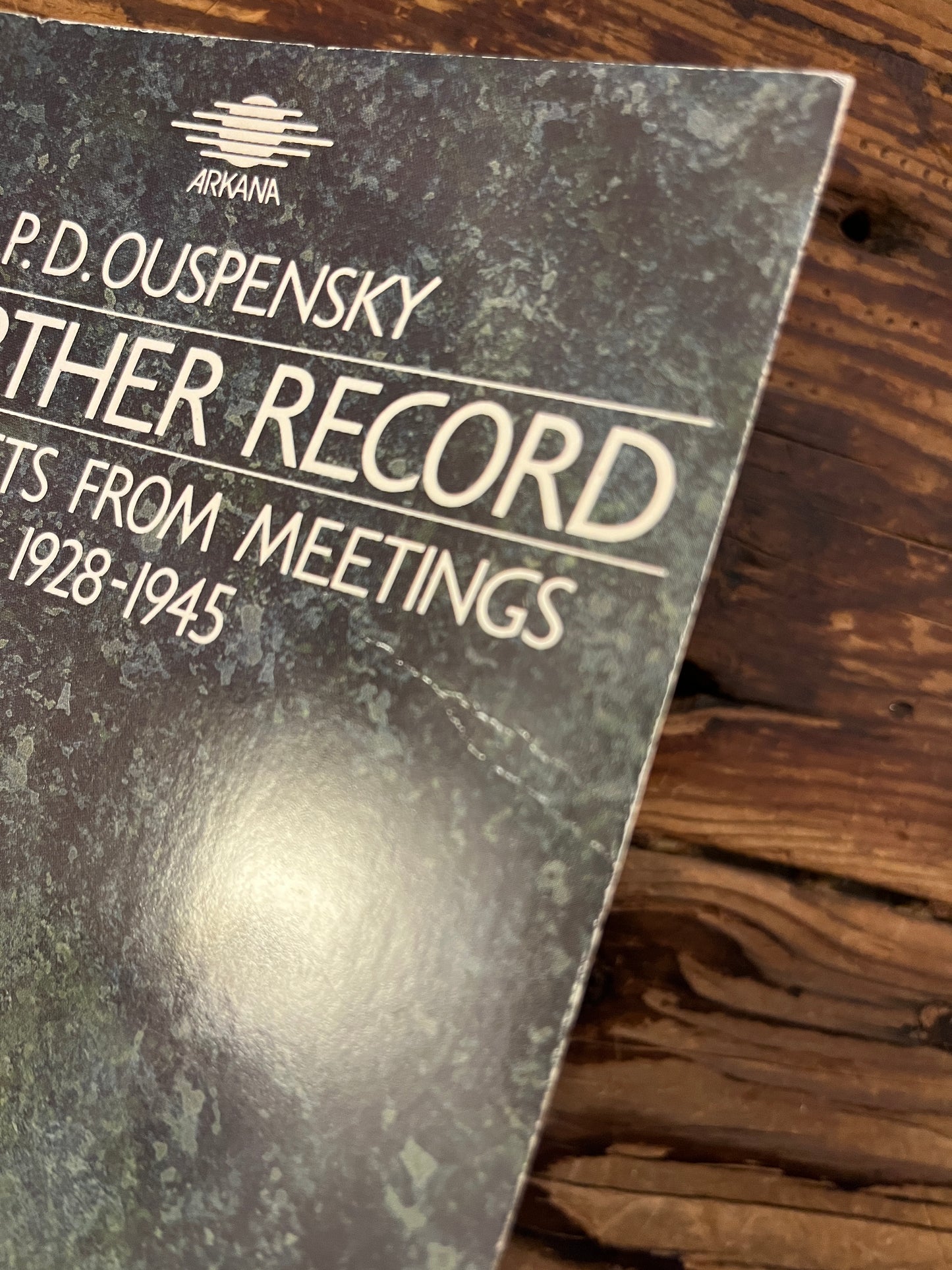 Corner of book titled 'a further record' by P.D. Ouspensky on a wooden surface 