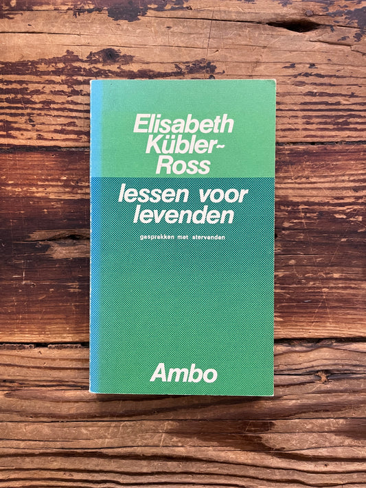 Voorkant van boek met de titel 'lessen voor levenden' door Elisabeth Kübler-Ross   op een houten achtergrond 