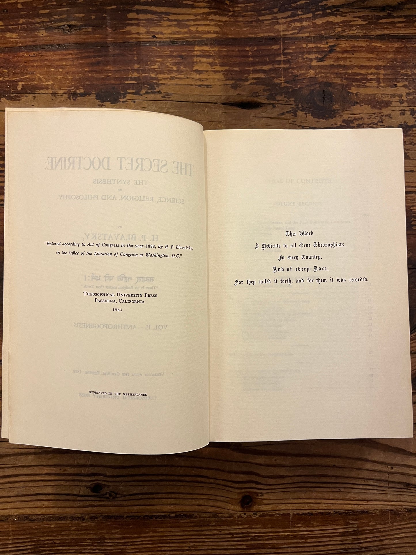 Open book titled 'The Secret Doctrine' by H.P. Blavatsky on a wooden surface.