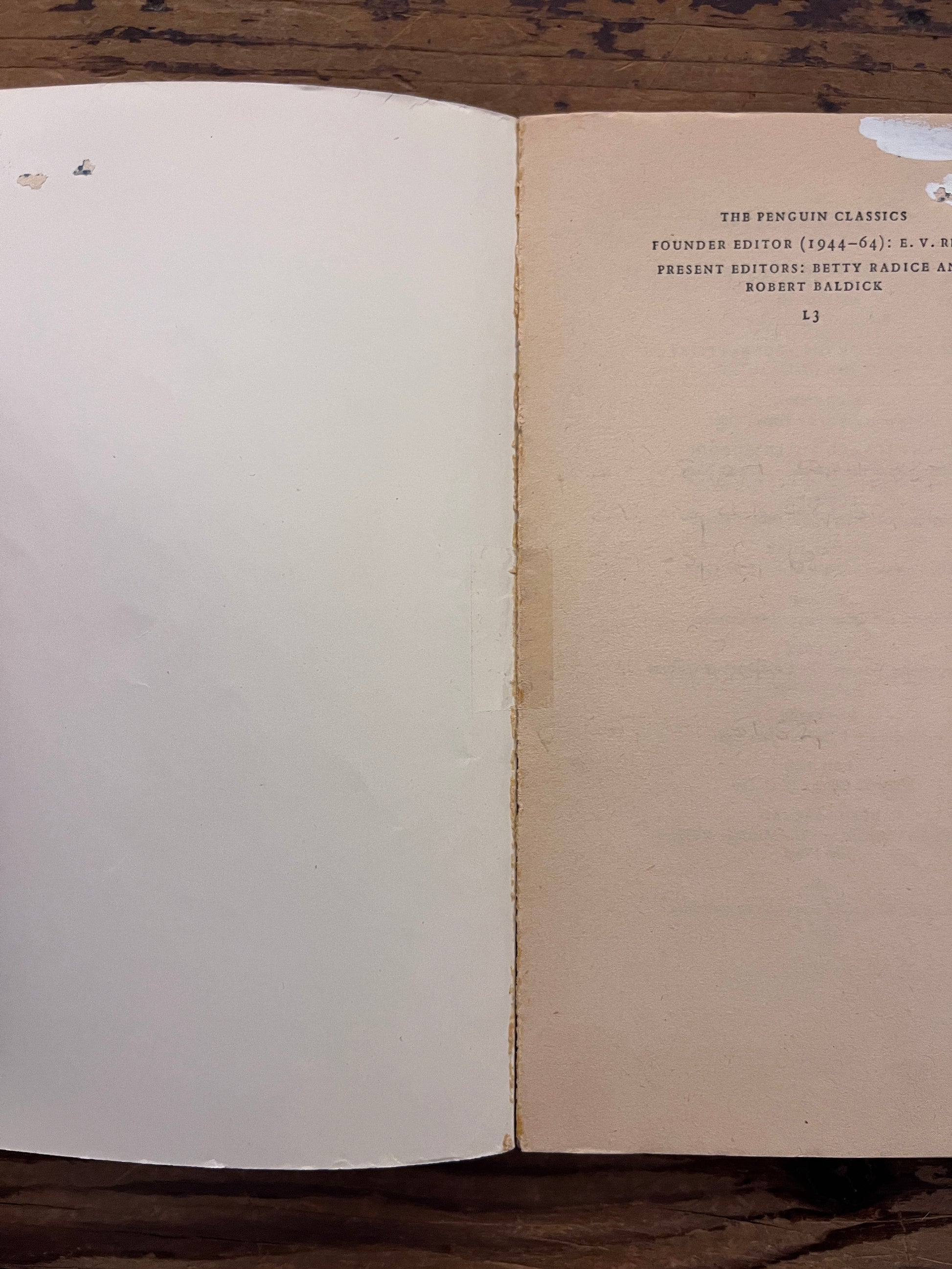 Open book titled 'the theban plays' by Sophocles on a wooden surface
