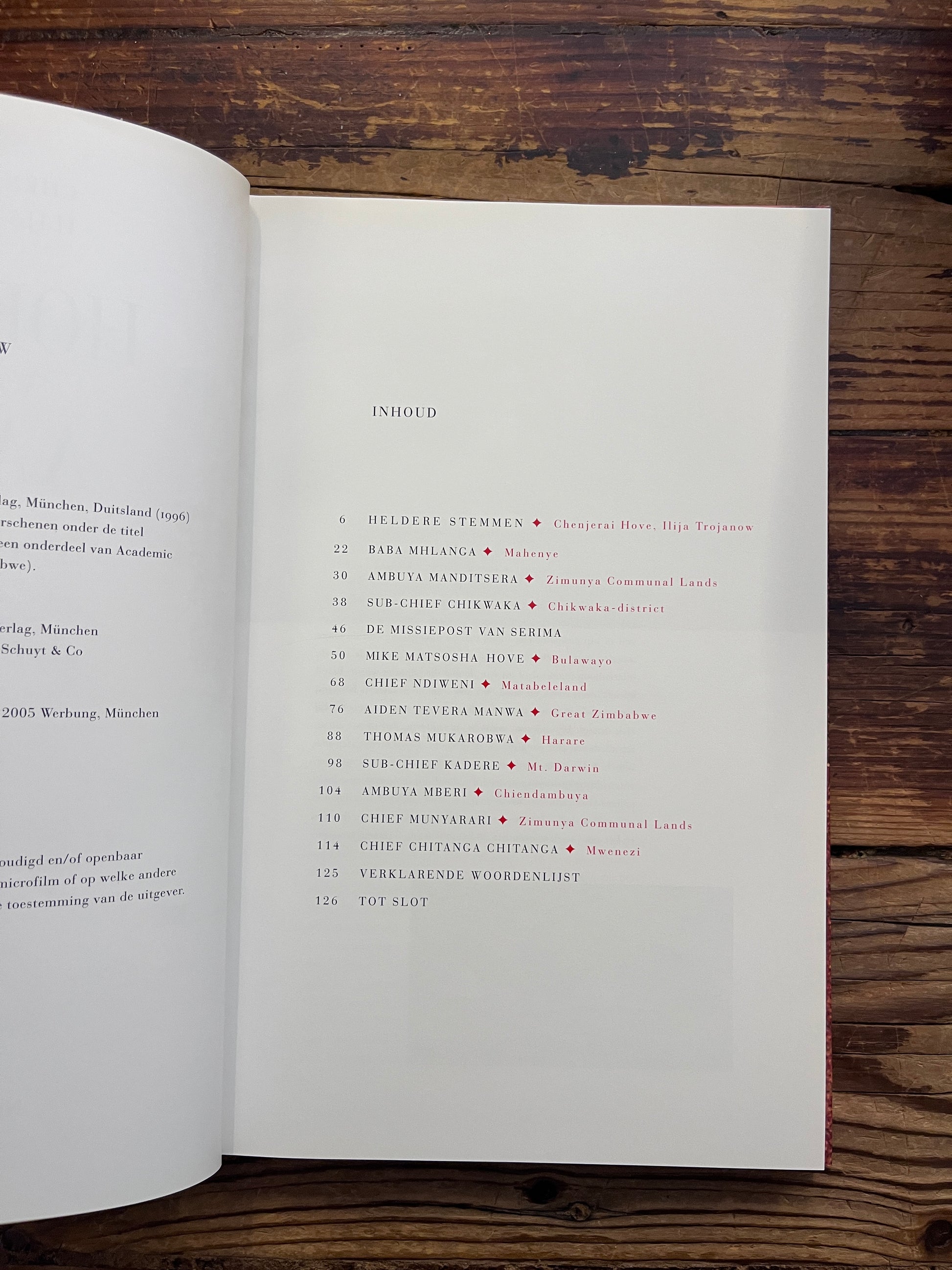 Open boek met de titel 'Hoeders van de Aarde' door Chenjerai Hove en Ilija Trojanow op een houten achtergrond 