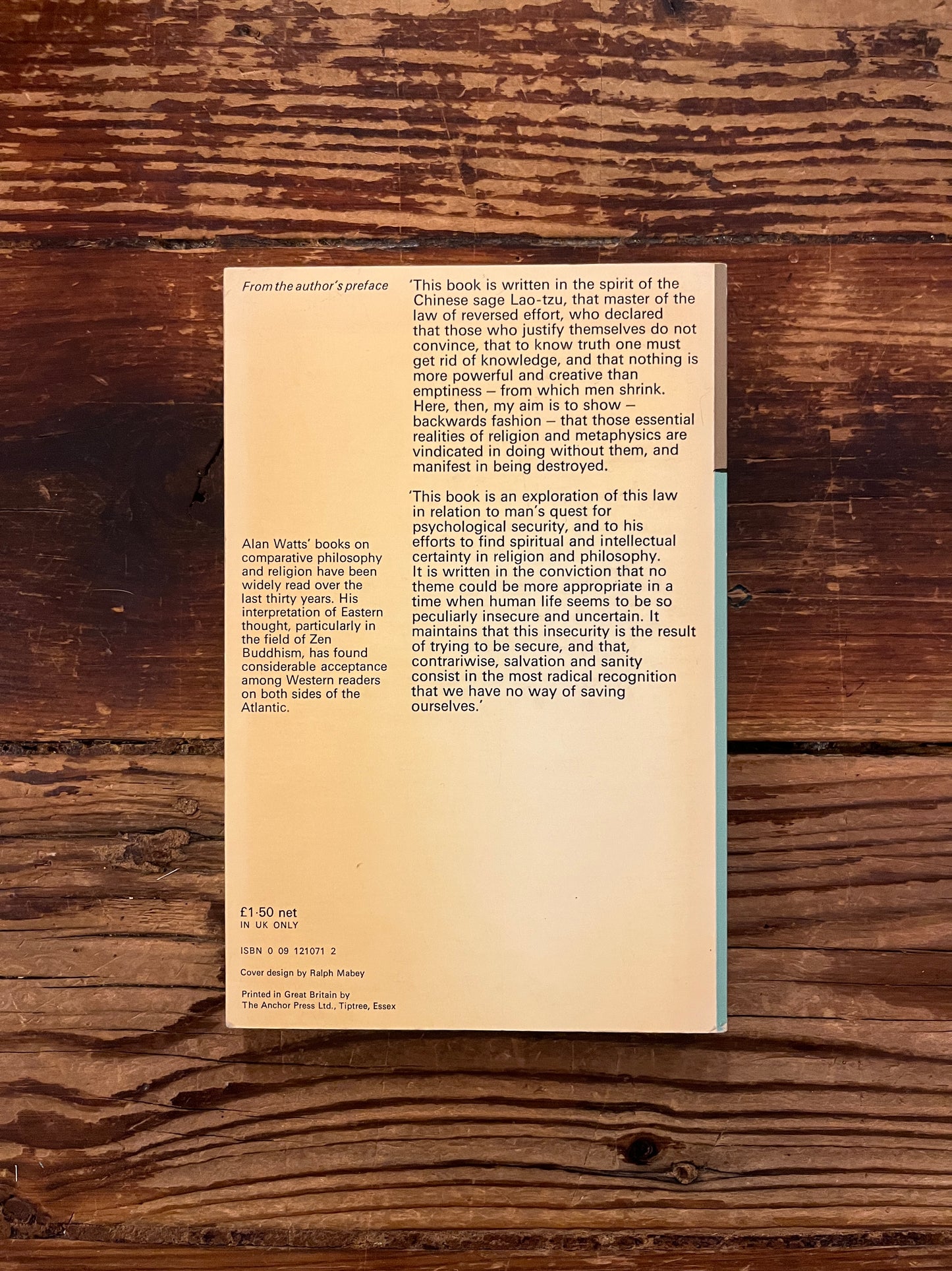 Back cover of 'The Wisdom of Insecurity' by Alan W. Watts on a wooden surface