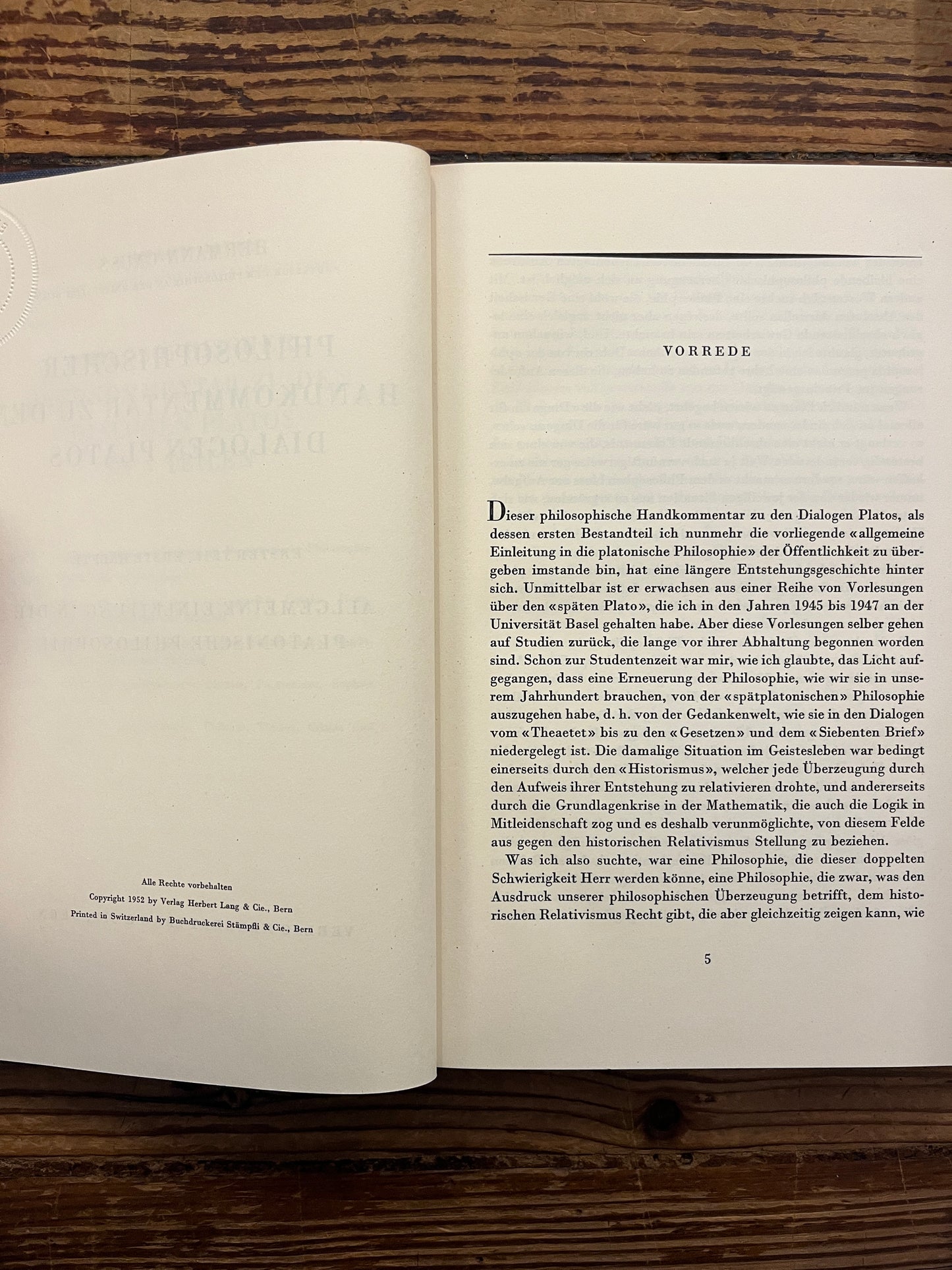 Open book titled 'Philosophischer Handkommentar zu den Dialogen Platos' by H. Gauss on a wooden surface 