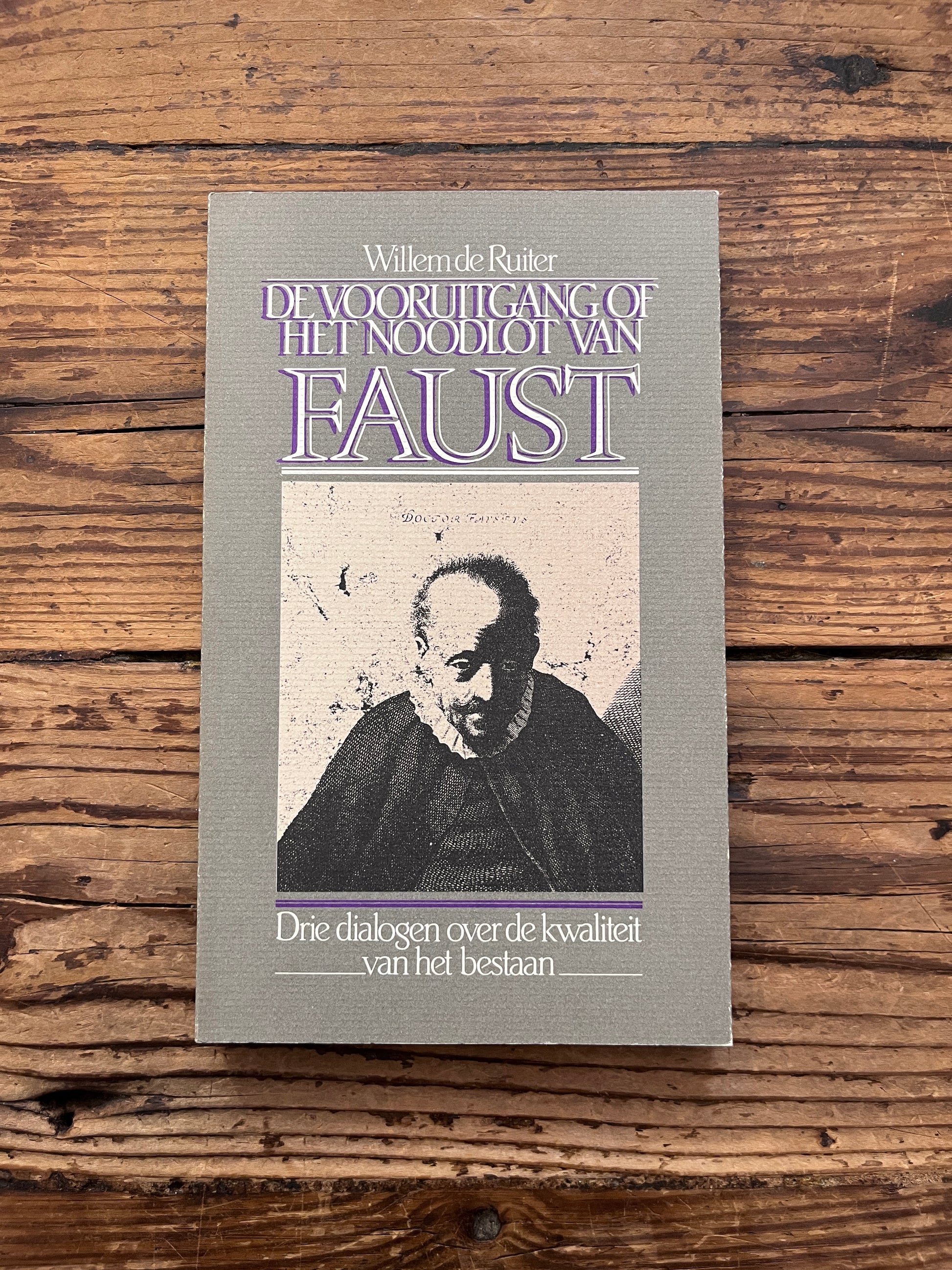 foto van de omslag van het boek de "vooruitgang of het noodlot van faust" op houten achtergrond