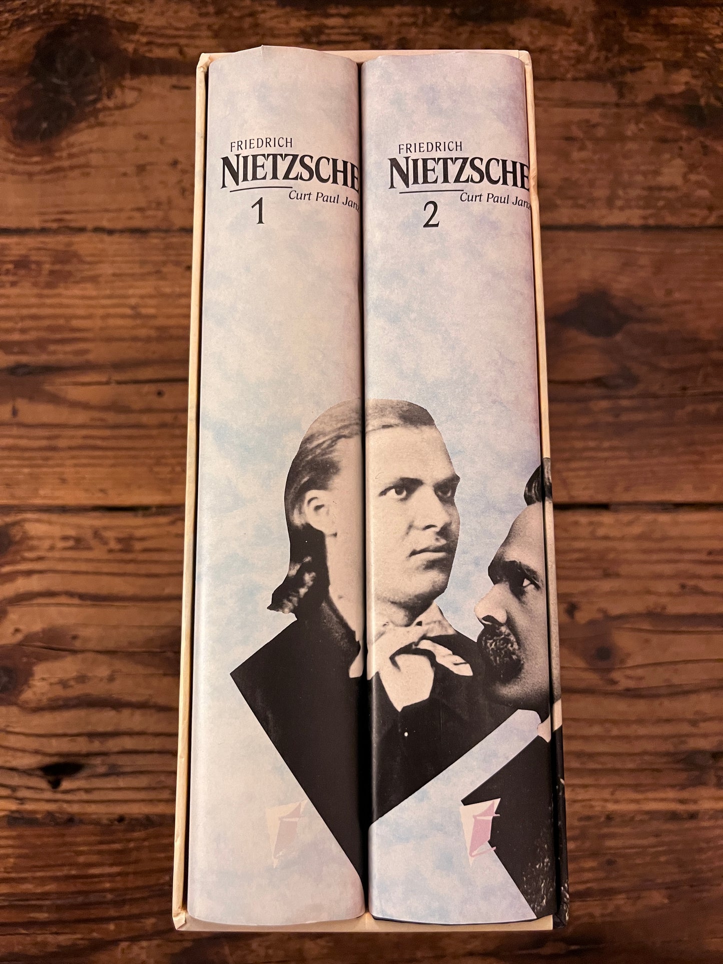 foto van de zijkant va de cassette waar de ruggen van beide boeken te zien zijn op een houten achtergrond