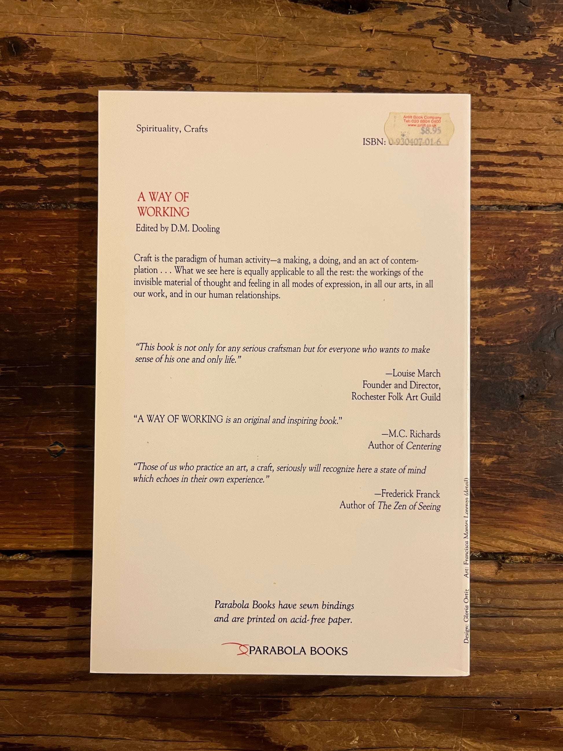 Back cover of book titled ' A way of working, the spiritual dimension of craft' on a wooden surface