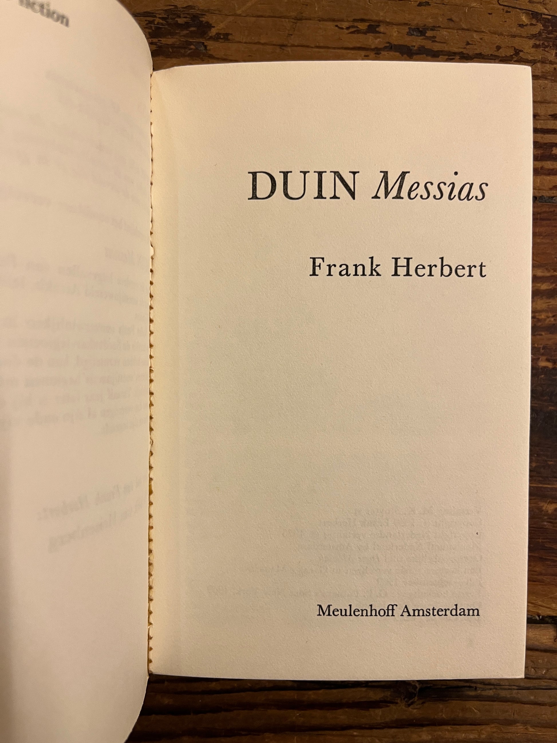Open boek op titel pagina, boek met de titel 'Duin Messias' door Frank Herbert op een houten achtergrond