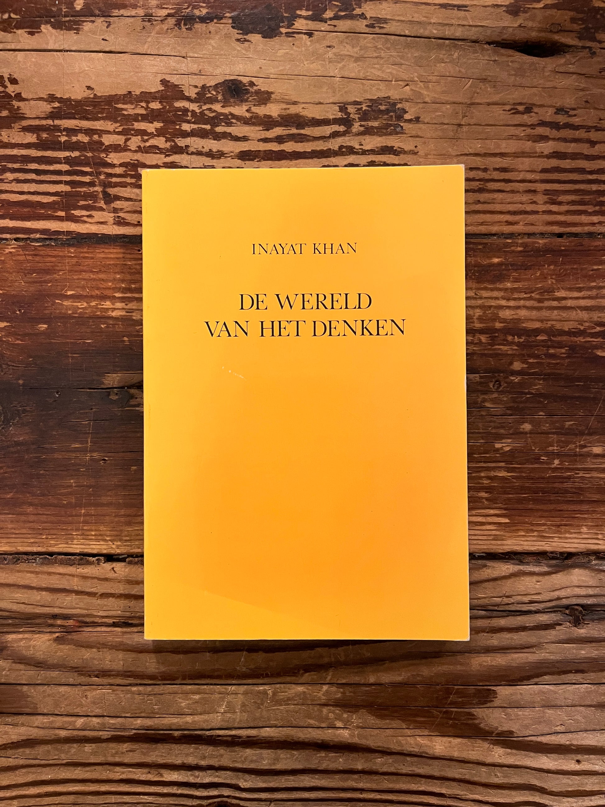 Voorkant van boek 'De Wereld van het Denken'  door Inayat Khan on a wooden surface