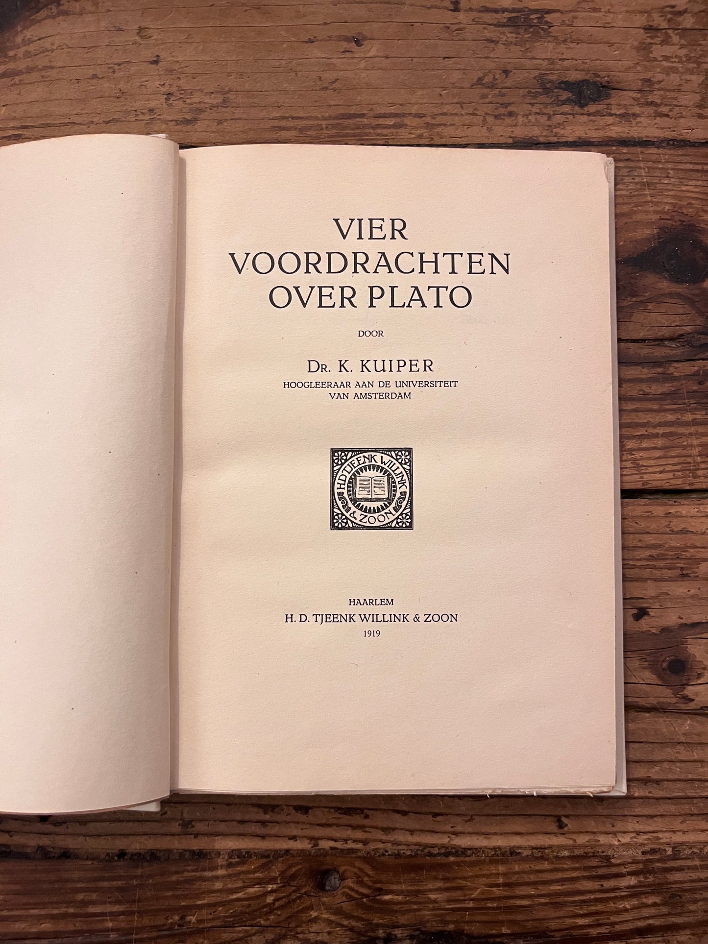 foto van de titel pagina van het boek "vier voordrachten over plato"  op houten achtergrond