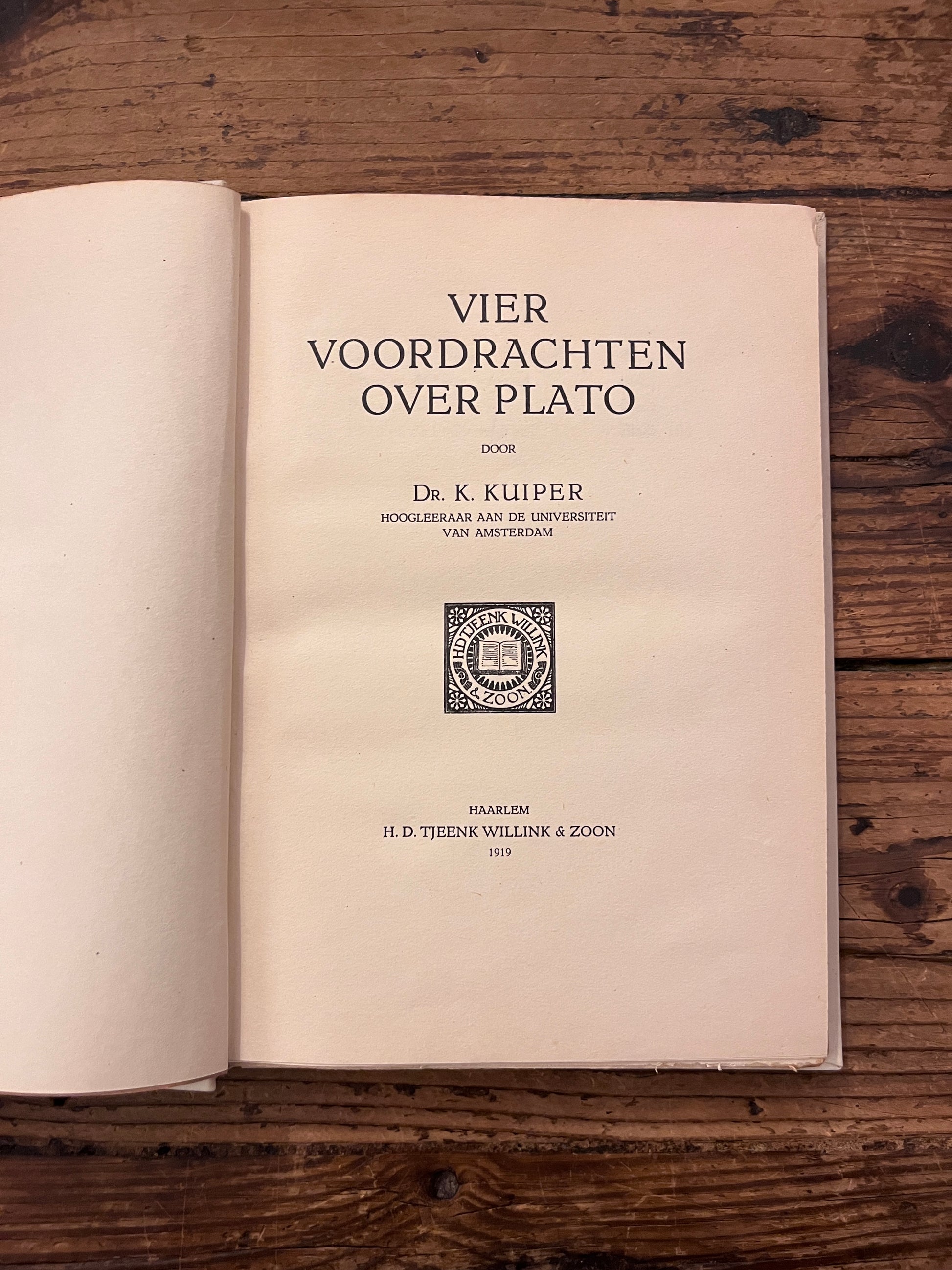 foto van de titel pagina van het boek "vier voordrachten over plato"  op houten achtergrond