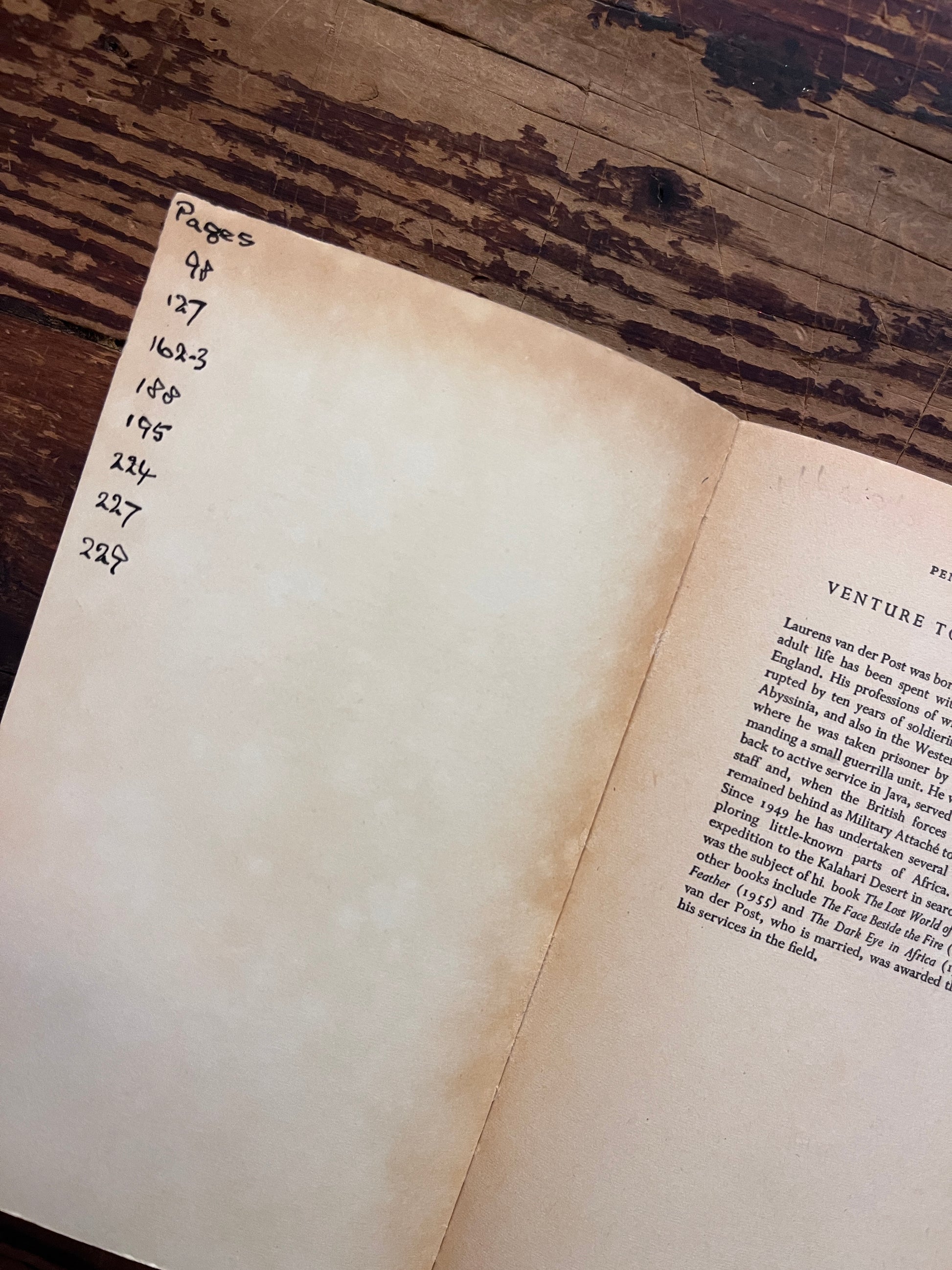 Open book titled 'venture to the interior' by Laurens van der Post on a wooden surface 