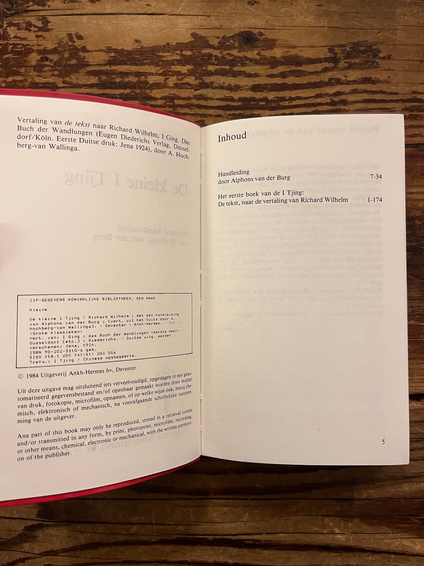 Open Boek met de titel 'de kleine I Tjing' op een houten achtergrond 