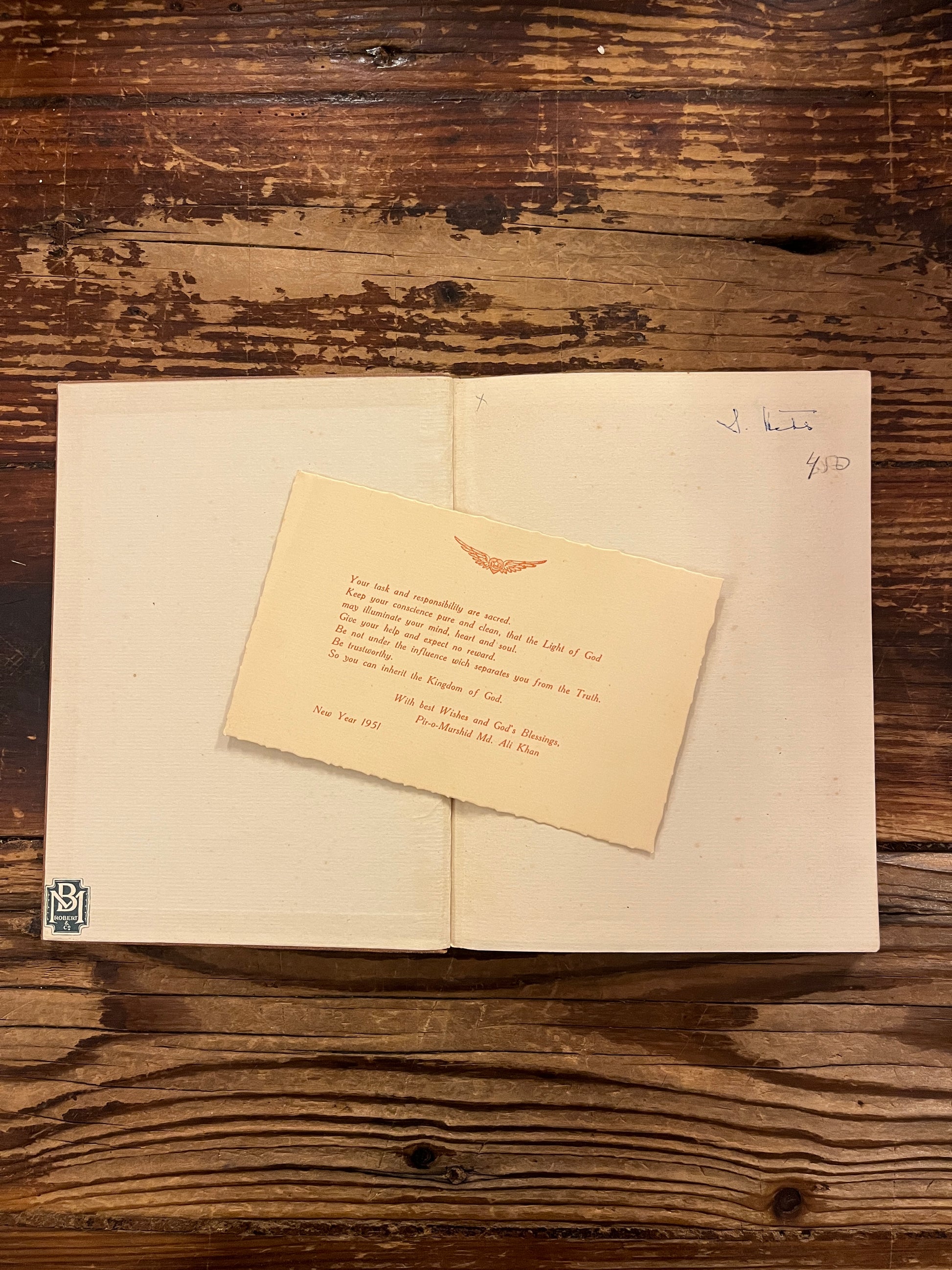 Open book titled 'The Purpose of Life'  by Inayat Khan on a wooden surface