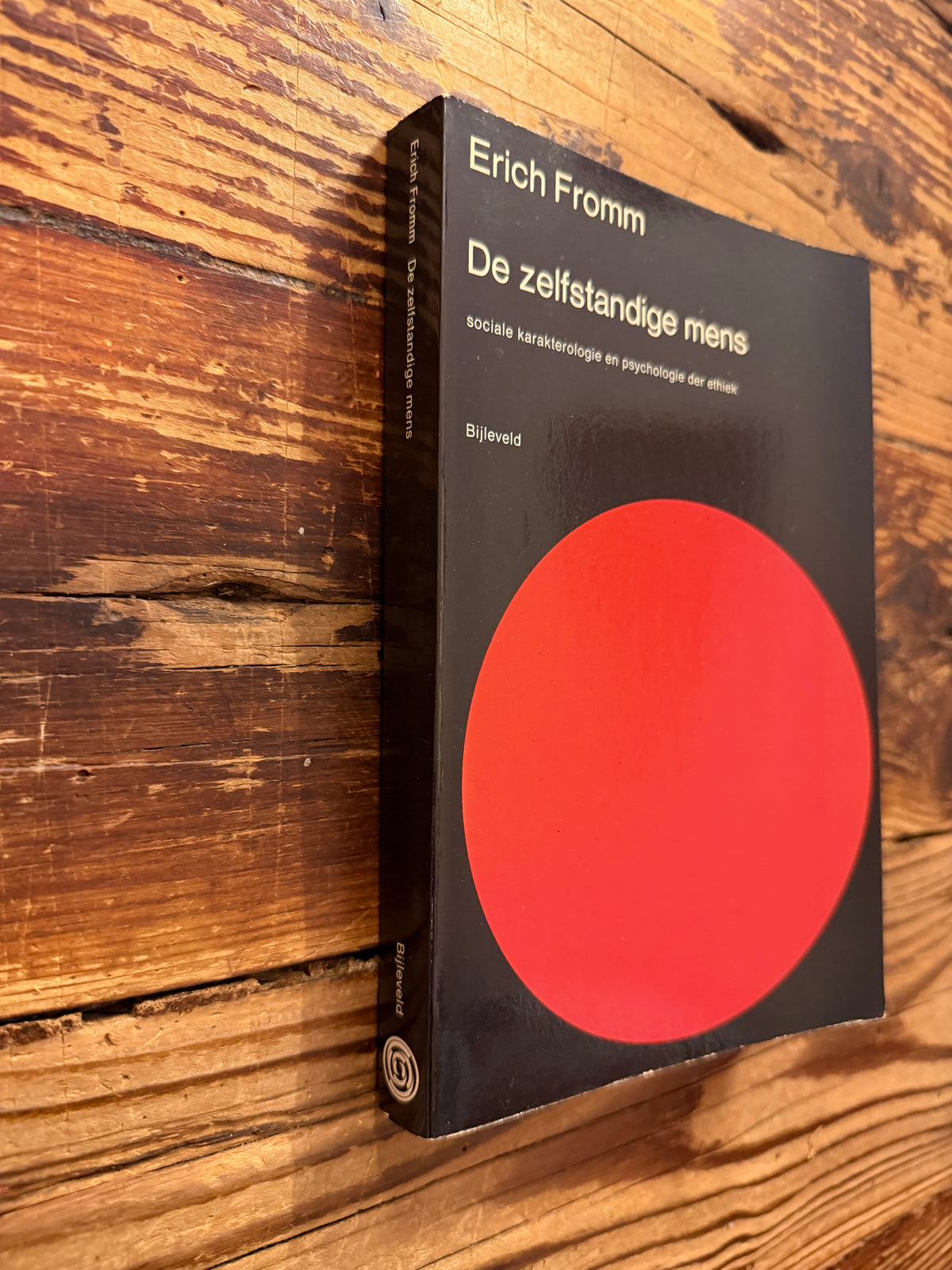 Voorkant en rug van een boek met de titel 'De zelfstandige mens' door Erich Fromm op een houten achtergrond 