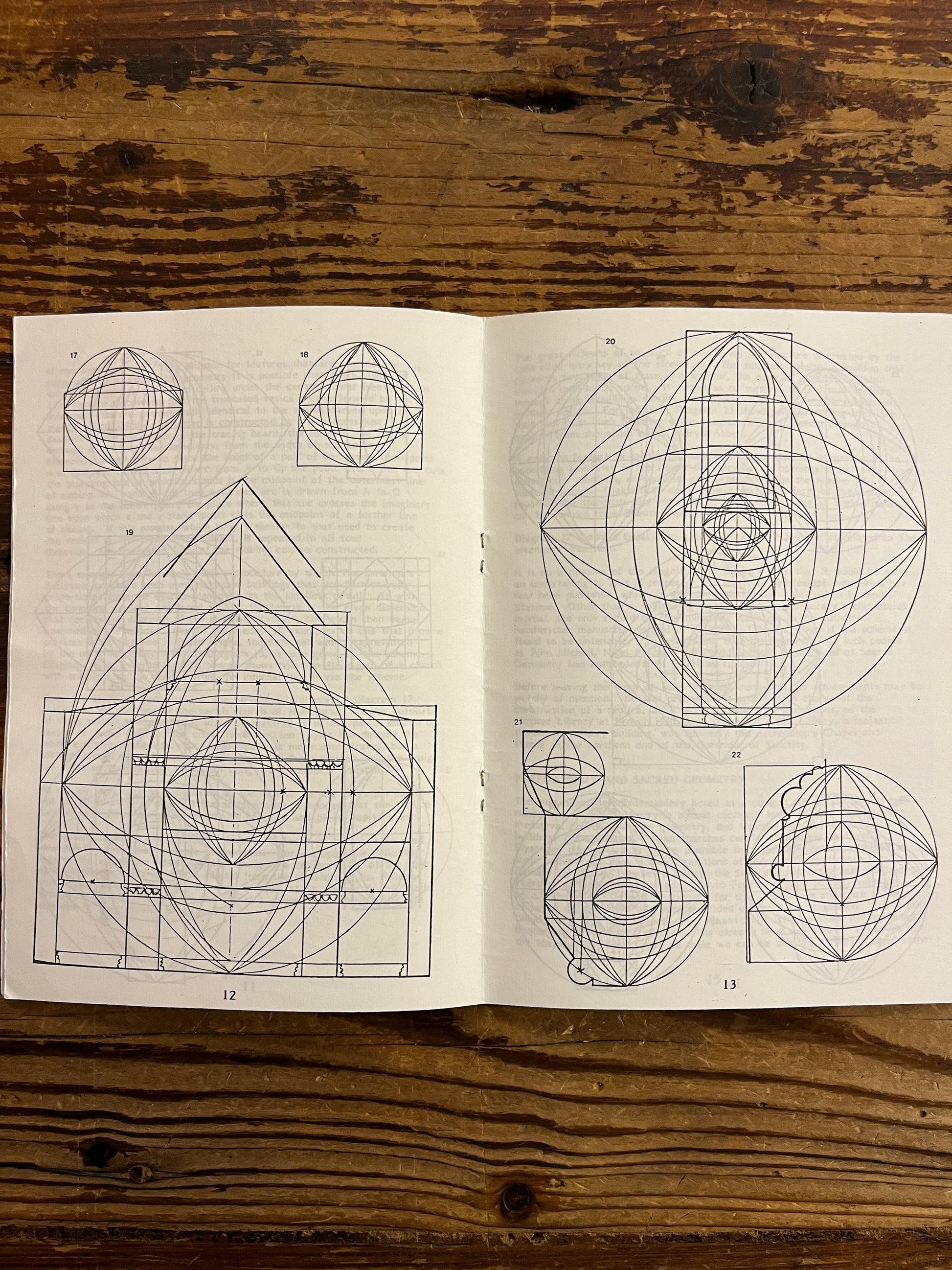 Open book with geometric drawings on a wooden surface