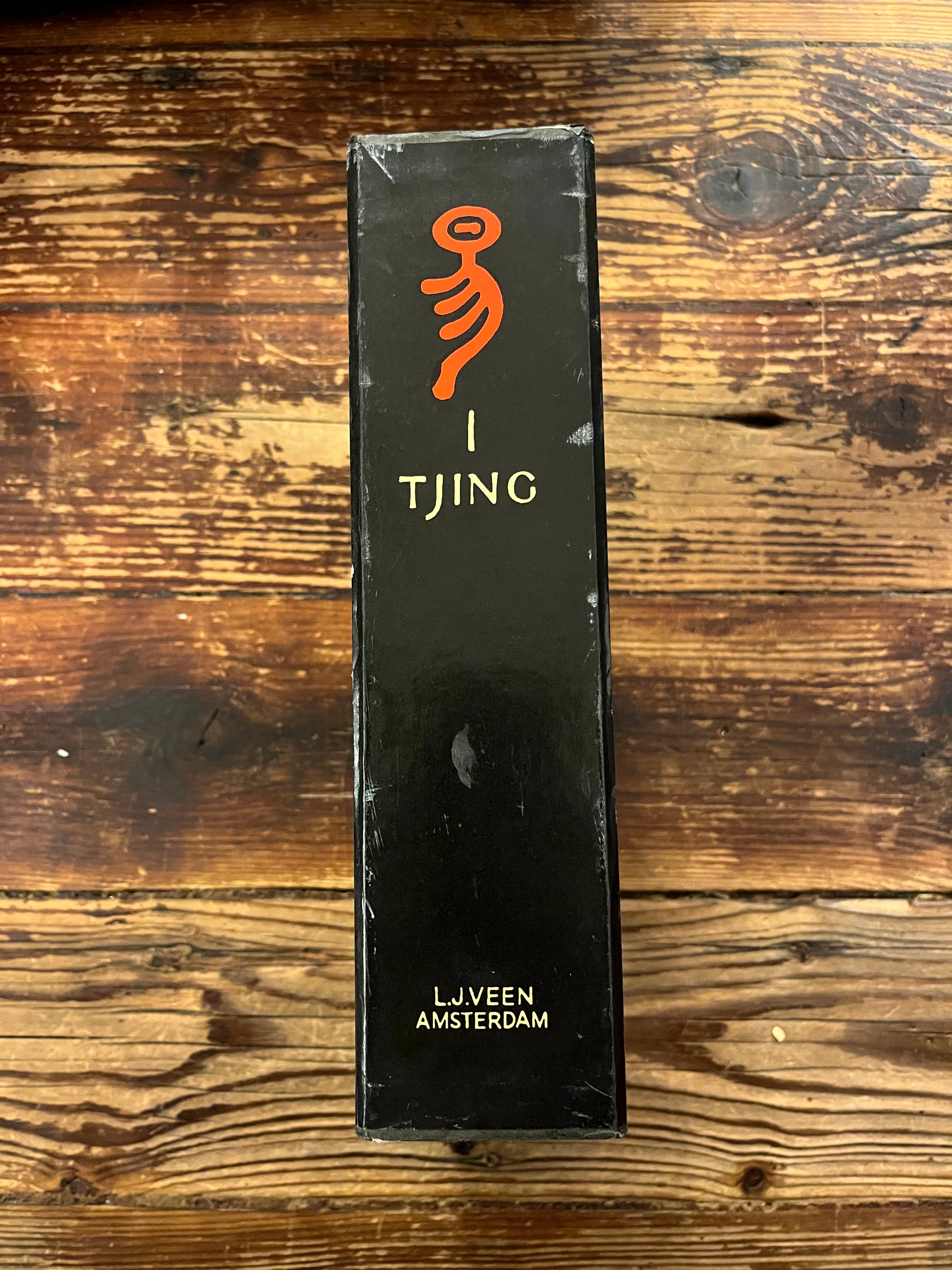 Rug van casette met twee boeken met de titel 'I Tjing: Het Boek Der Veranderingen' op een houten achtergrond