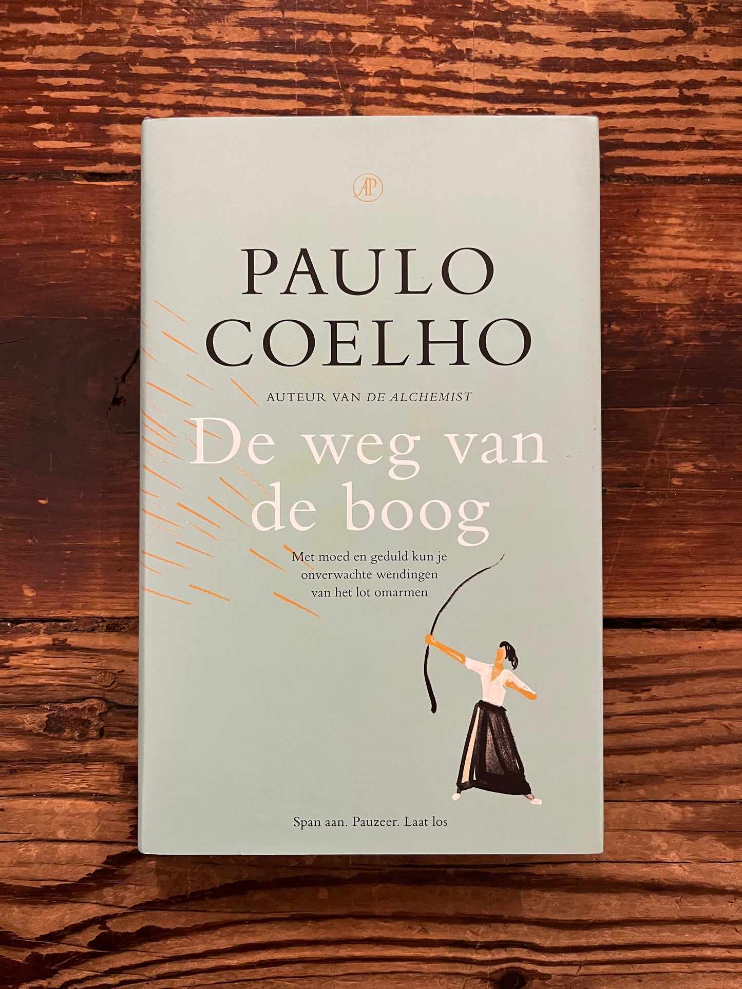 Boek 'de weg van de boog' door Paulo Coelho op een houten achtergrond 