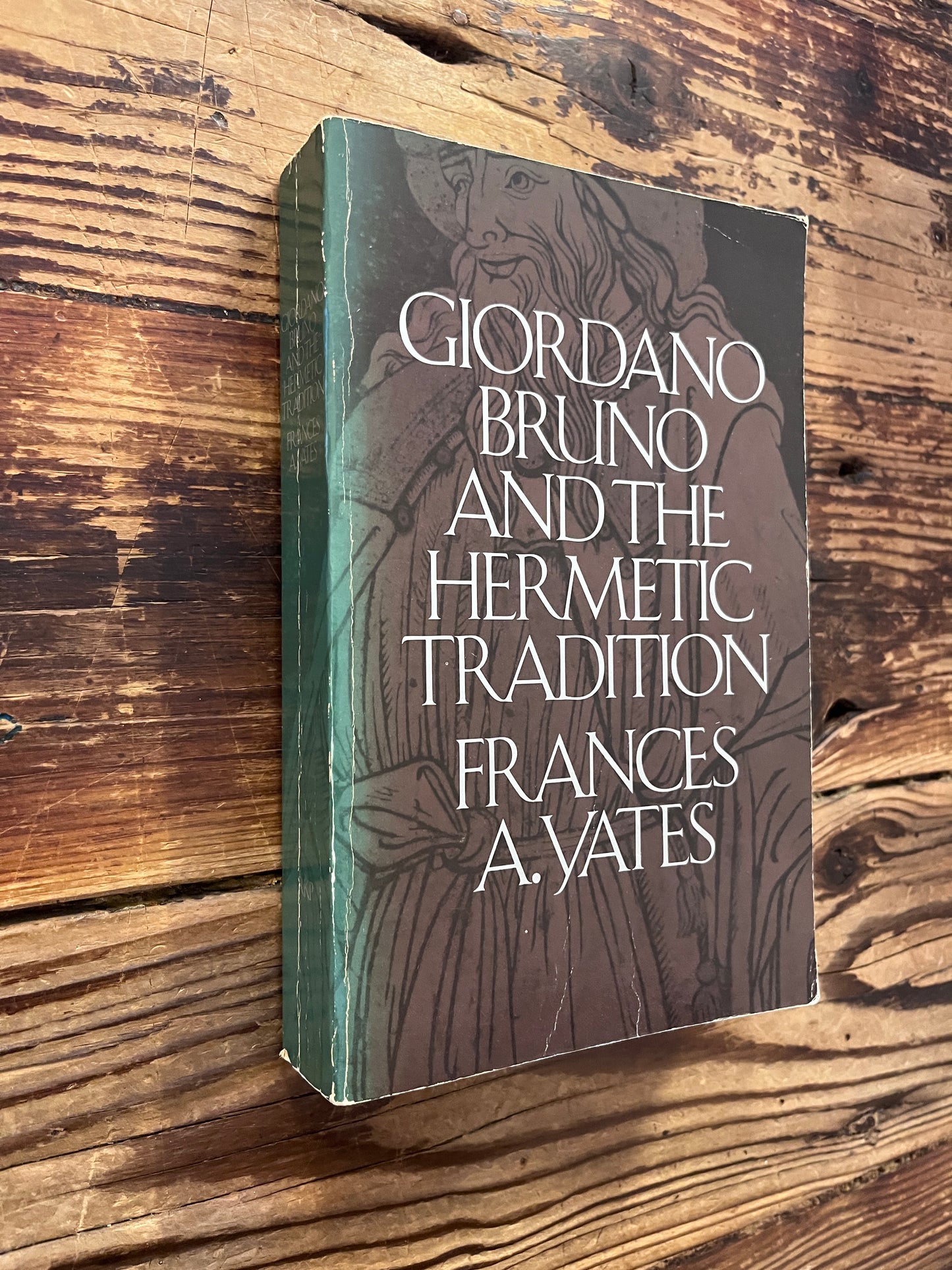 Front cover and spine of a book titled 'Giordano Bruno and the Hermetic Tradition' by Frances A. Yates lying on a wooden surface