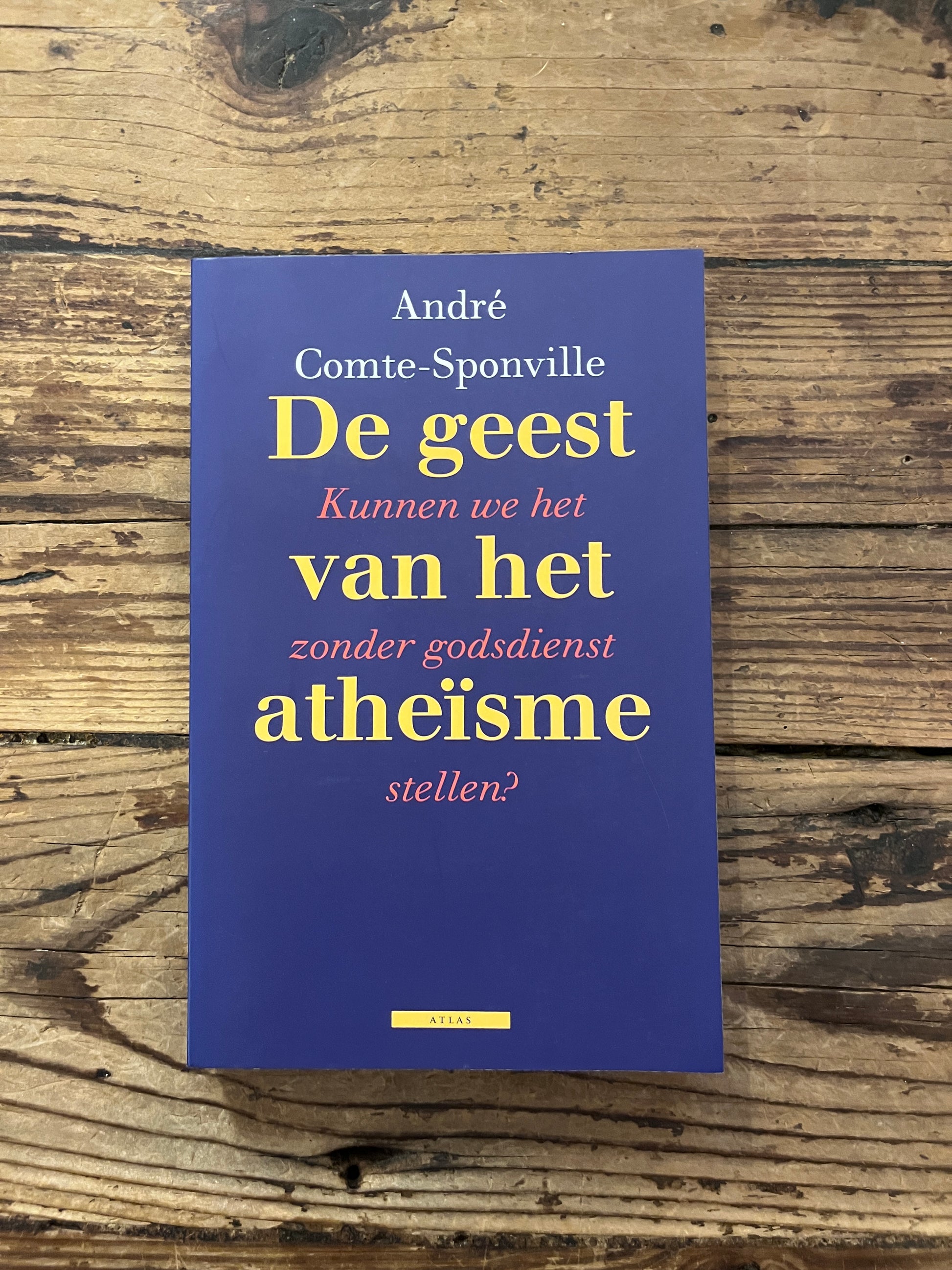 foto van de omslag van het boek "de geest van atheisme" op houten achtergrond