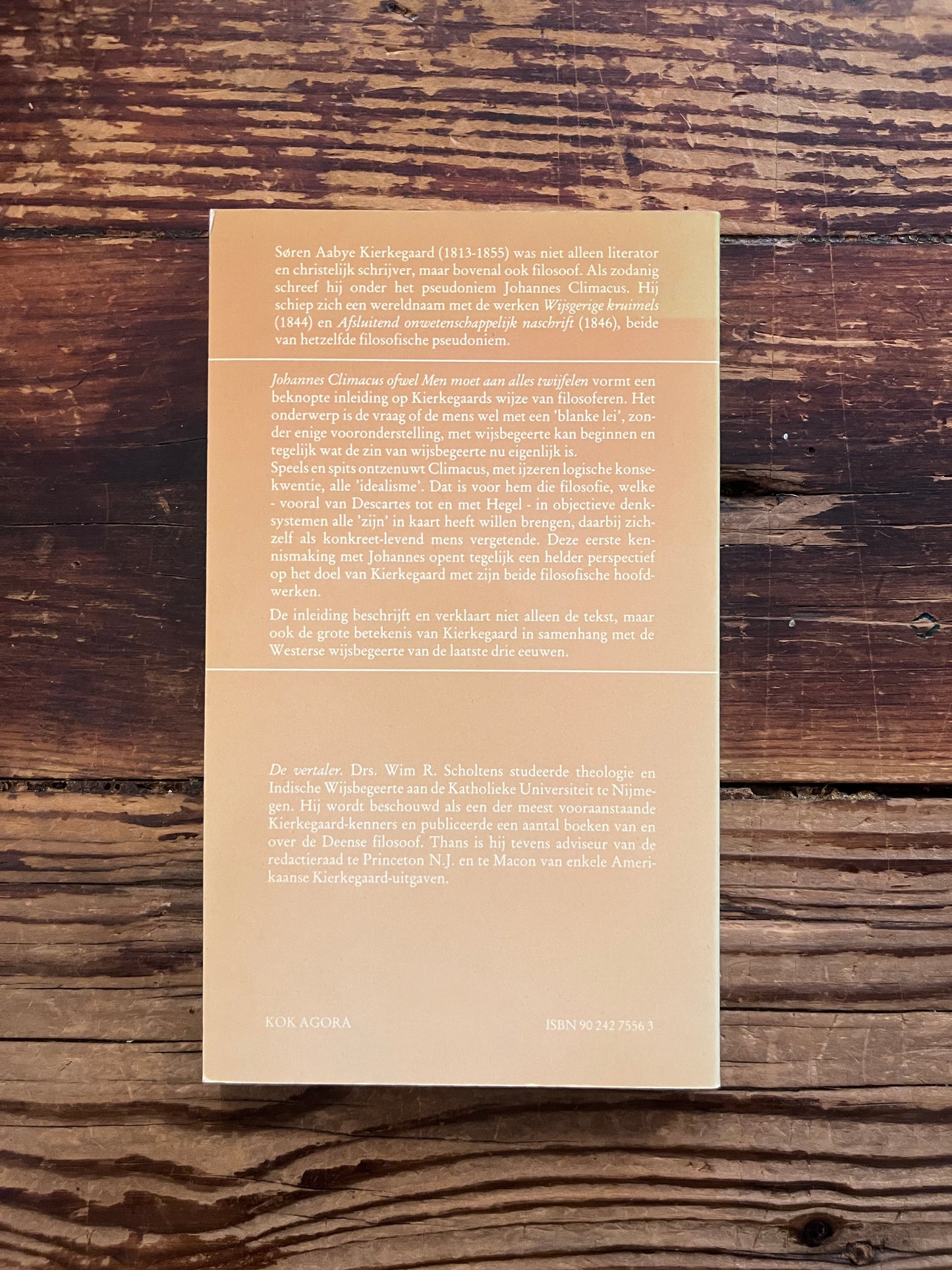 foto van de backcover van het boek "men moet aan alles twijfelen" op houten achtergrond