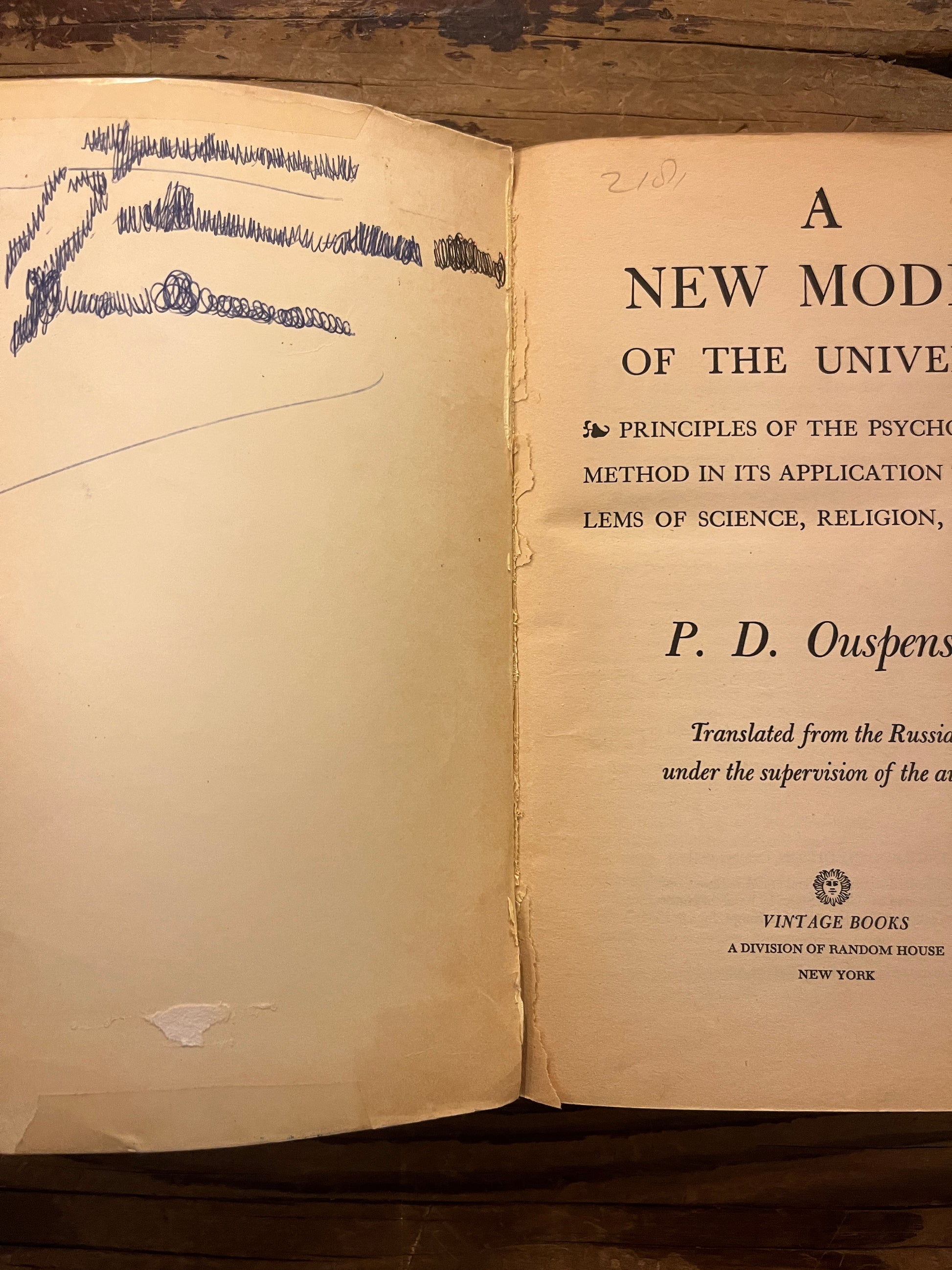 Open Book titled 'A New Model of the Universe' by P.D. Ouspensky on a wooden surface