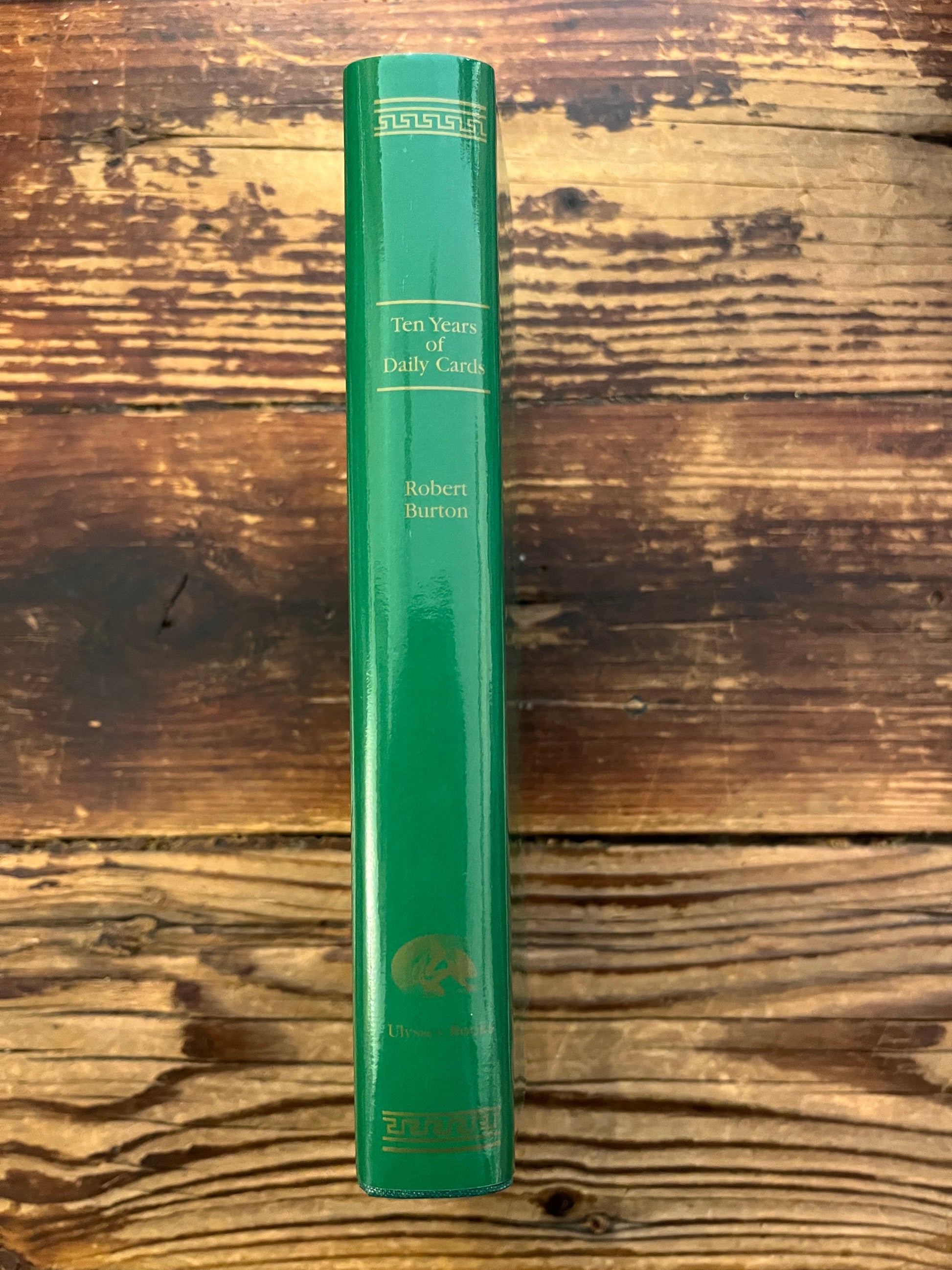 spine of book with the title 'Ten Years of Daily Cards' by Robert Burton on a wooden surface