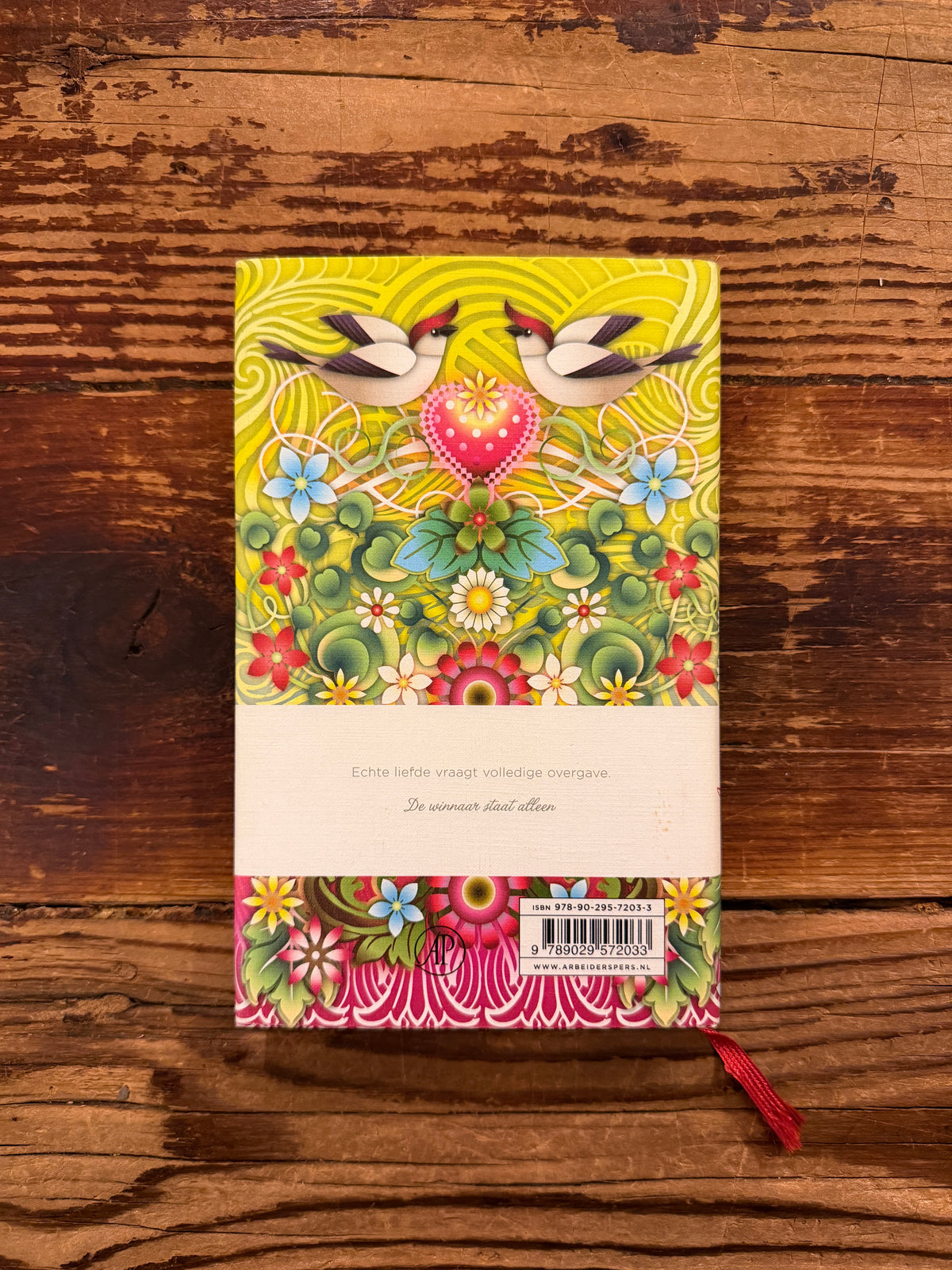 Achterkant van boek met de titel 'liefde' door Paulo Coelho op een houten achtergrond